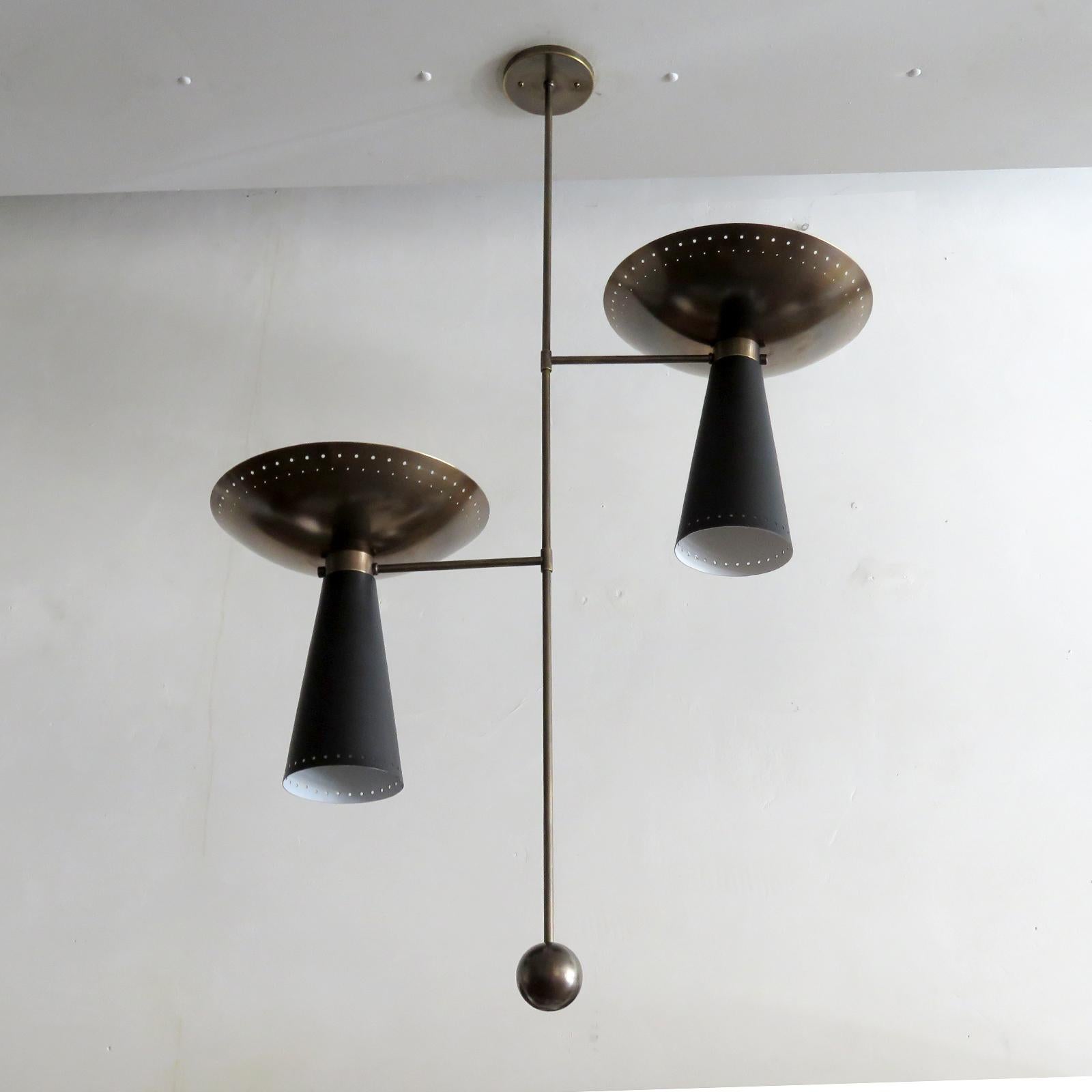 Elegante Pendelleuchte Calice II, entworfen von Gallery L7, handgefertigt in Los Angeles aus amerikanischem Messing, mit zwei gealterten Messing-Uplights und zwei schwarz emaillierten Down-Lights. Perforation entlang der Ränder und Kugel aus