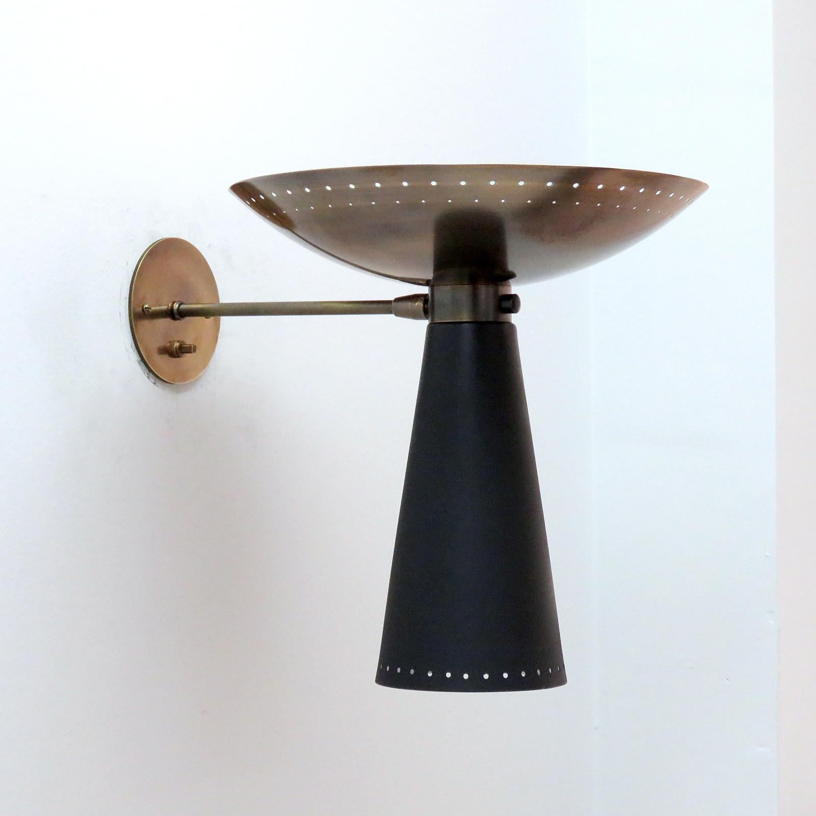 wonderful articulate Calice wall lights designed by Gallery L7, handcrafted and finished in Los Angeles from American brass, with an aged brass up-light and a black enameled down-light. Perforations along the rims and on/off switch on the solid