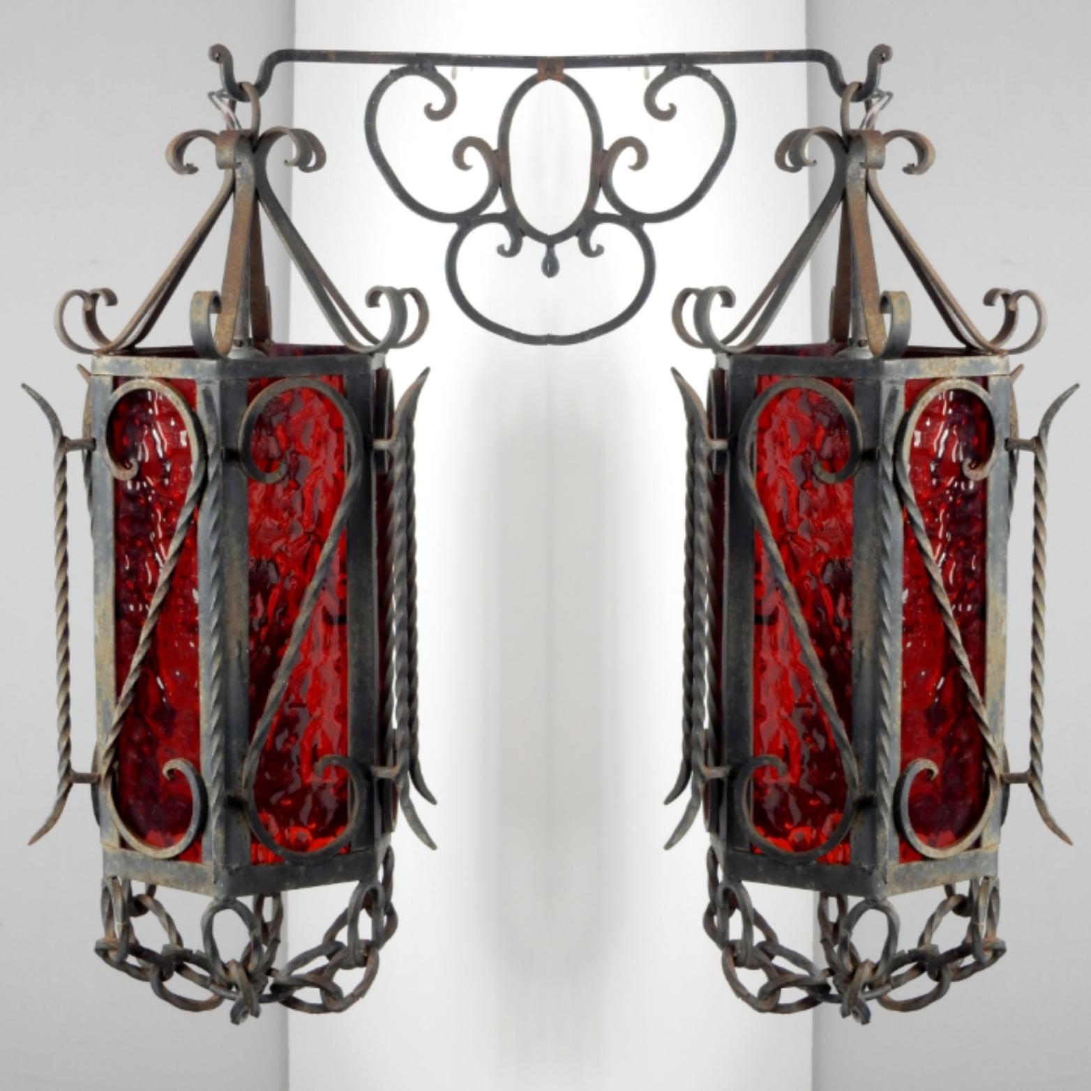 Pair of ornate wrought iron garden/patio sconces. 
6 sided with original ruby red wavy glass.
Circa 1950's.
 