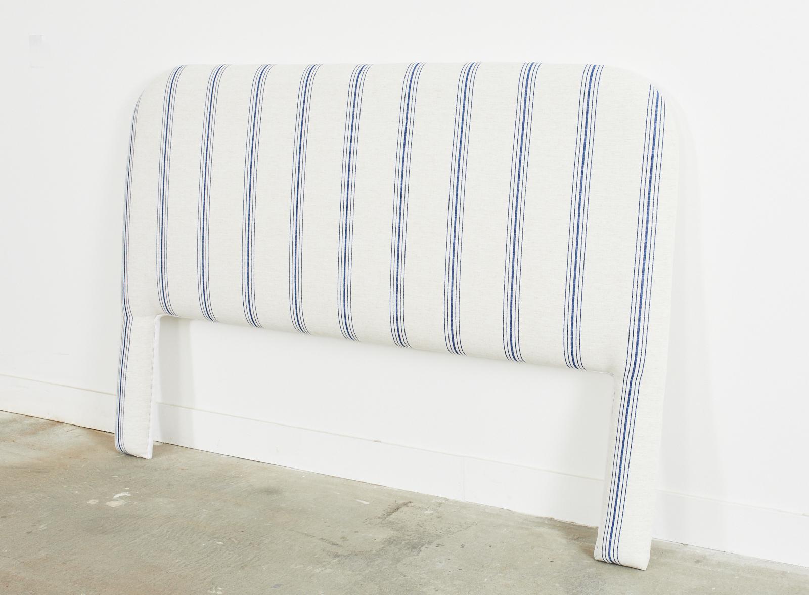 Stylish Cal king newly padded headboard redux featuring a soft striped blue and white linen style upholstery. The striped design is decorated with indigo blue and off-white stripes in an aged patina linen. The vintage headboard has a flat top crest