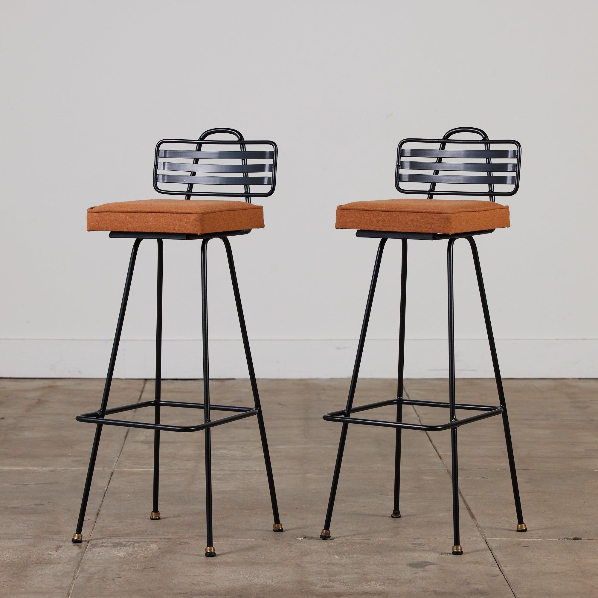 This bar height stool features a black powder coated tubular steel frame with a low slatted seat back and foot rest. The square seat cushions are upholstered in a burnt orange fabric. This would be great indoor or outdoor stool.

There are two