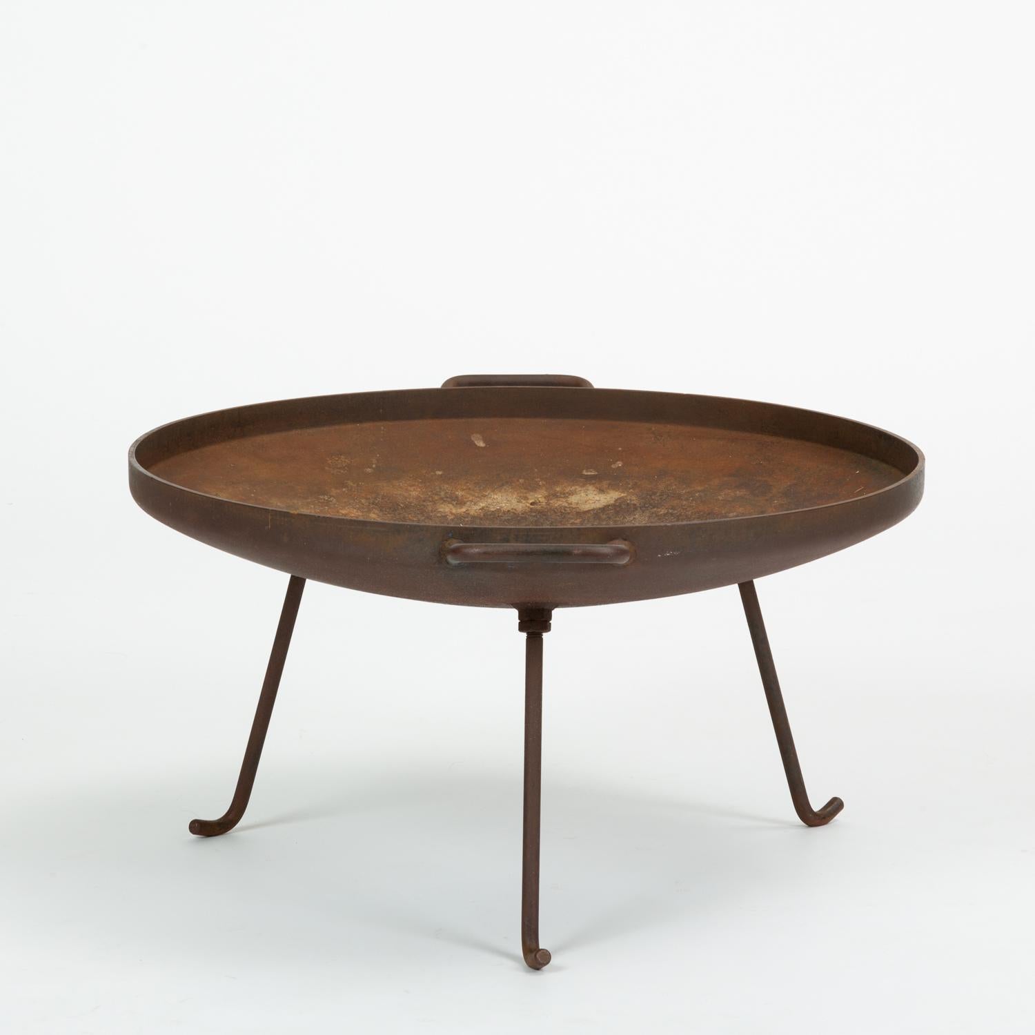 A three-legged iron barbecue or fire pit by Stan Hawk for his company Hawk House. A Case Study Program-approved design, the fire barbecue gave modernist form to an ancient instrument, sitting firmly on three iron legs with bent feet. The brazier
