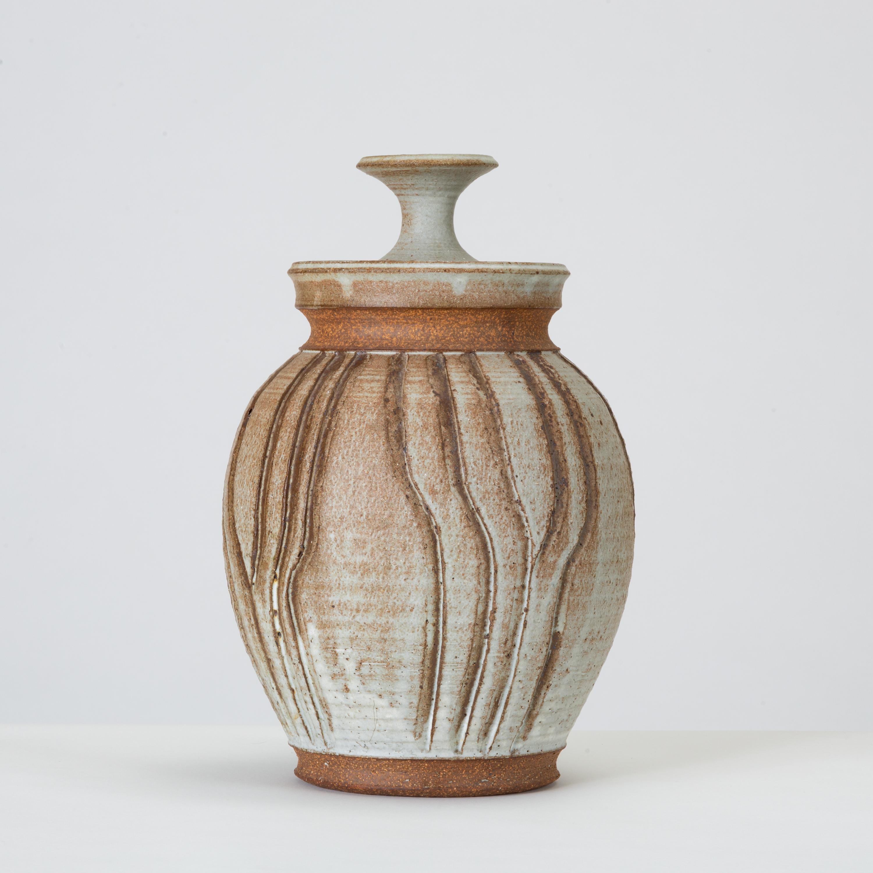 Don Jennings, a prominent local ceramicist based in Orange County, California, worked as an instructor and artist throughout the 1960s and 1970s. This example is a wheel-thrown ceramic lidded jar with a pleasing neutral palette of bone and chestnut