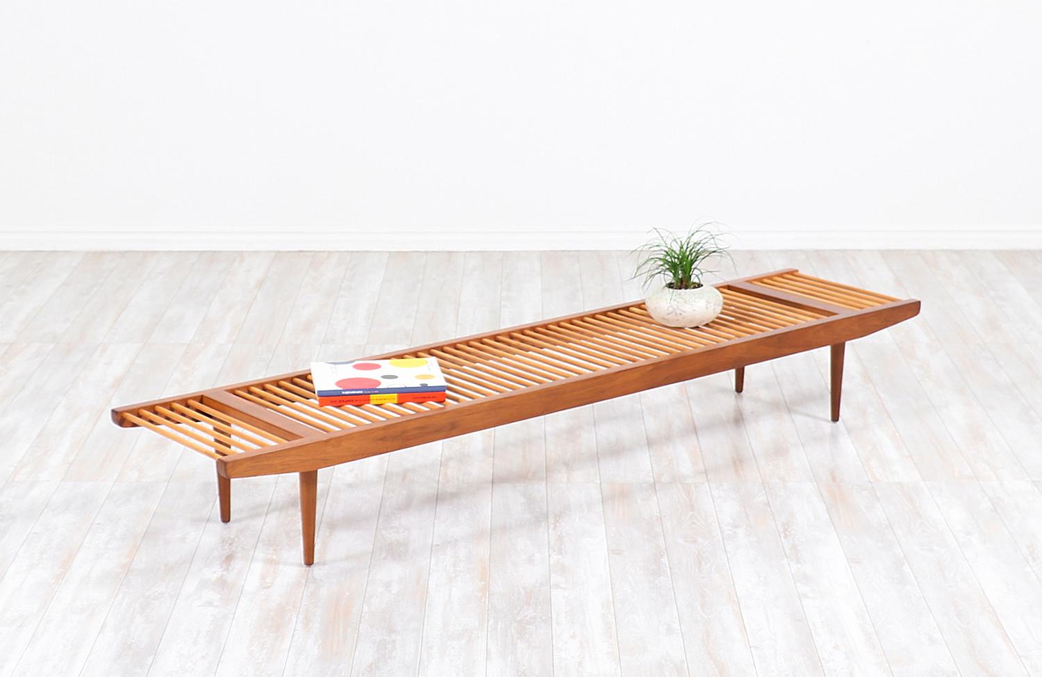 Elegant Californian modern bench designed by Milo Baughman for Glenn of California in the United States, circa 1950s. This beautiful large dowel bench features a solid low profile frame and is comprised of a lovely contrast of walnut wood and