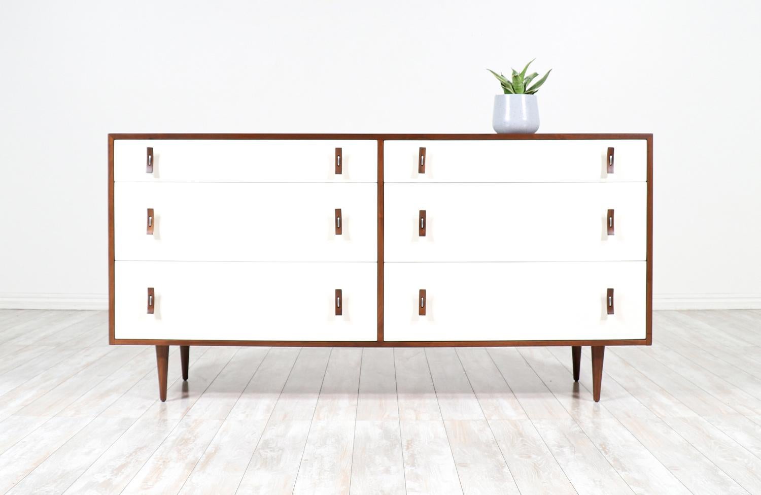 A beautiful six drawer dresser designed by Stanley Young for Glenn of California in the United States circa 1950s. This stylish dresser features the designer’s signature bentwood and steel pulls on each of the white lacquered drawers that open to