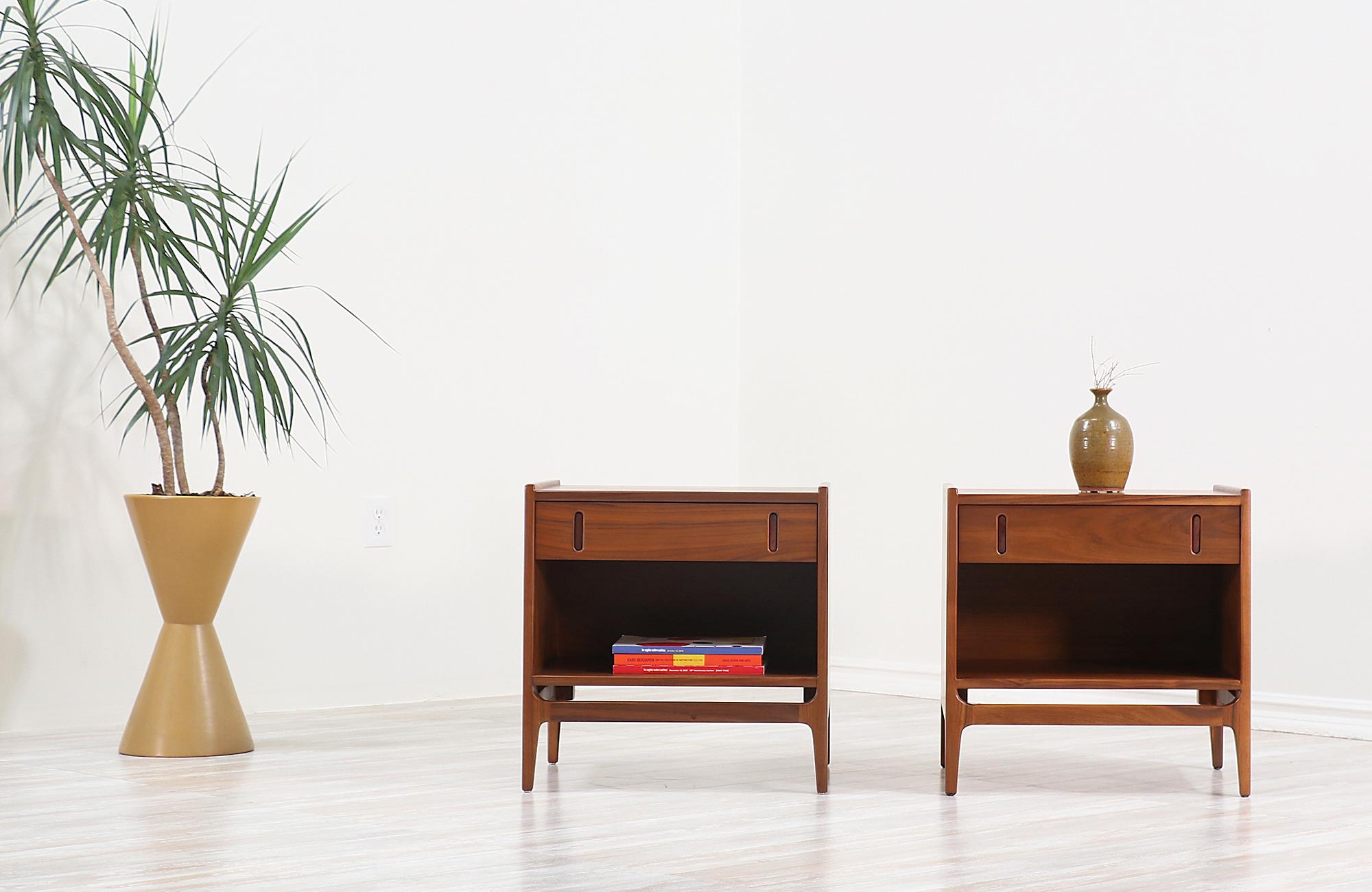 A pair of stylish modern nightstands designed by Richard Thompson for Glenn of California ‘Baronet’ line in the United States, circa 1950s. These sleek nightstands feature a sturdy walnut wood case with integrated legs, and retractable rosewood