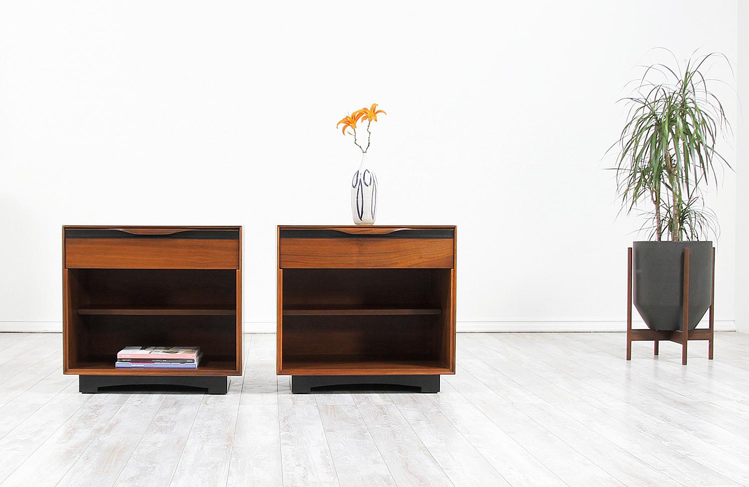 A pair of two modern nightstands designed by John Kapel for Glenn of California in the United States, circa 1950s. These practical and elegant pair features a walnut wood case with one top drawer and lower shelved storage space. The drawer shows