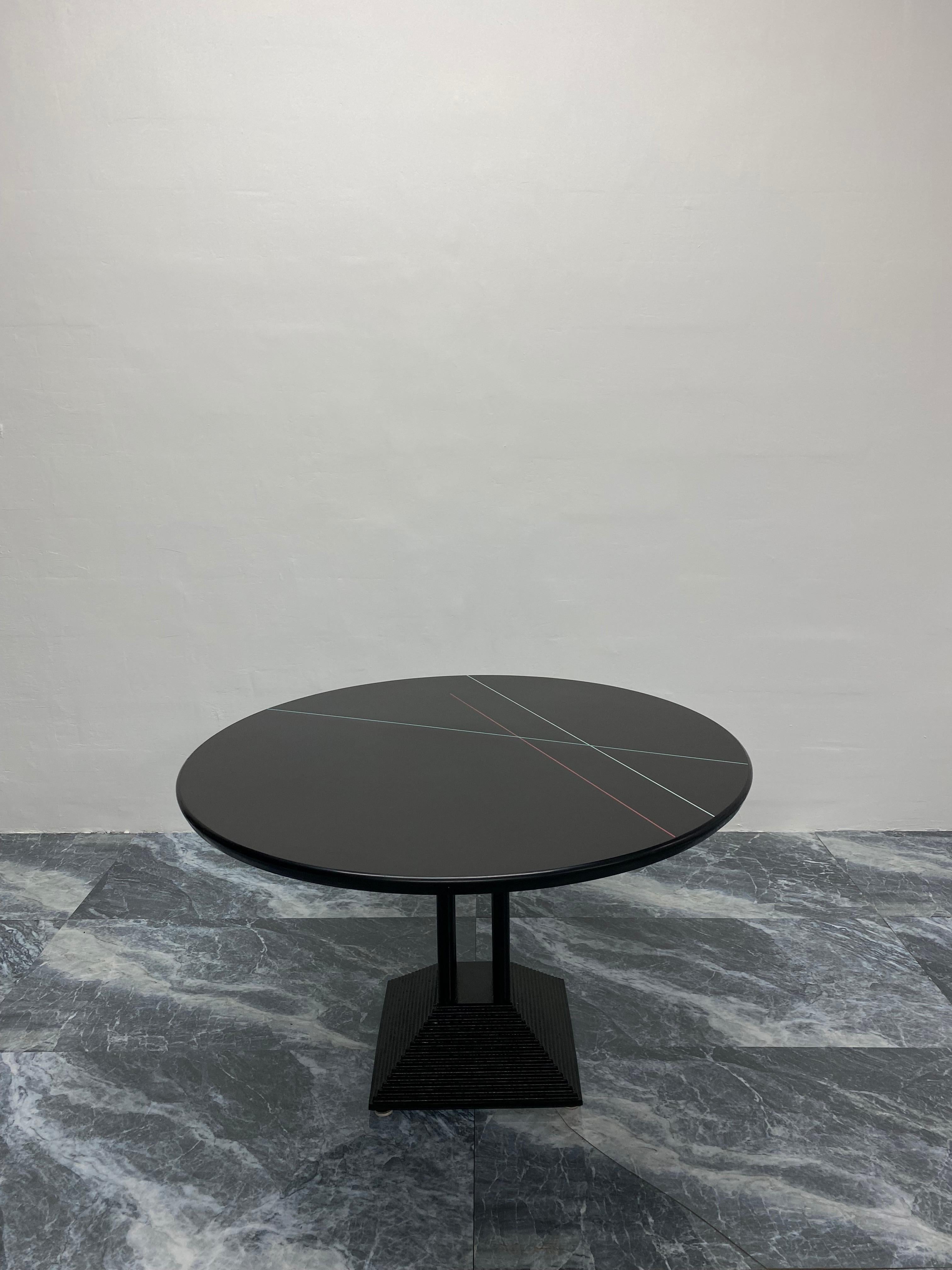 Black laminate wood top with colored lines and rubber outer edge dining table by Peterson Design Furniture out of California, 1980s. The top sits on four tubular steel poles connected to a pyramid shaped black lacquered steel base.