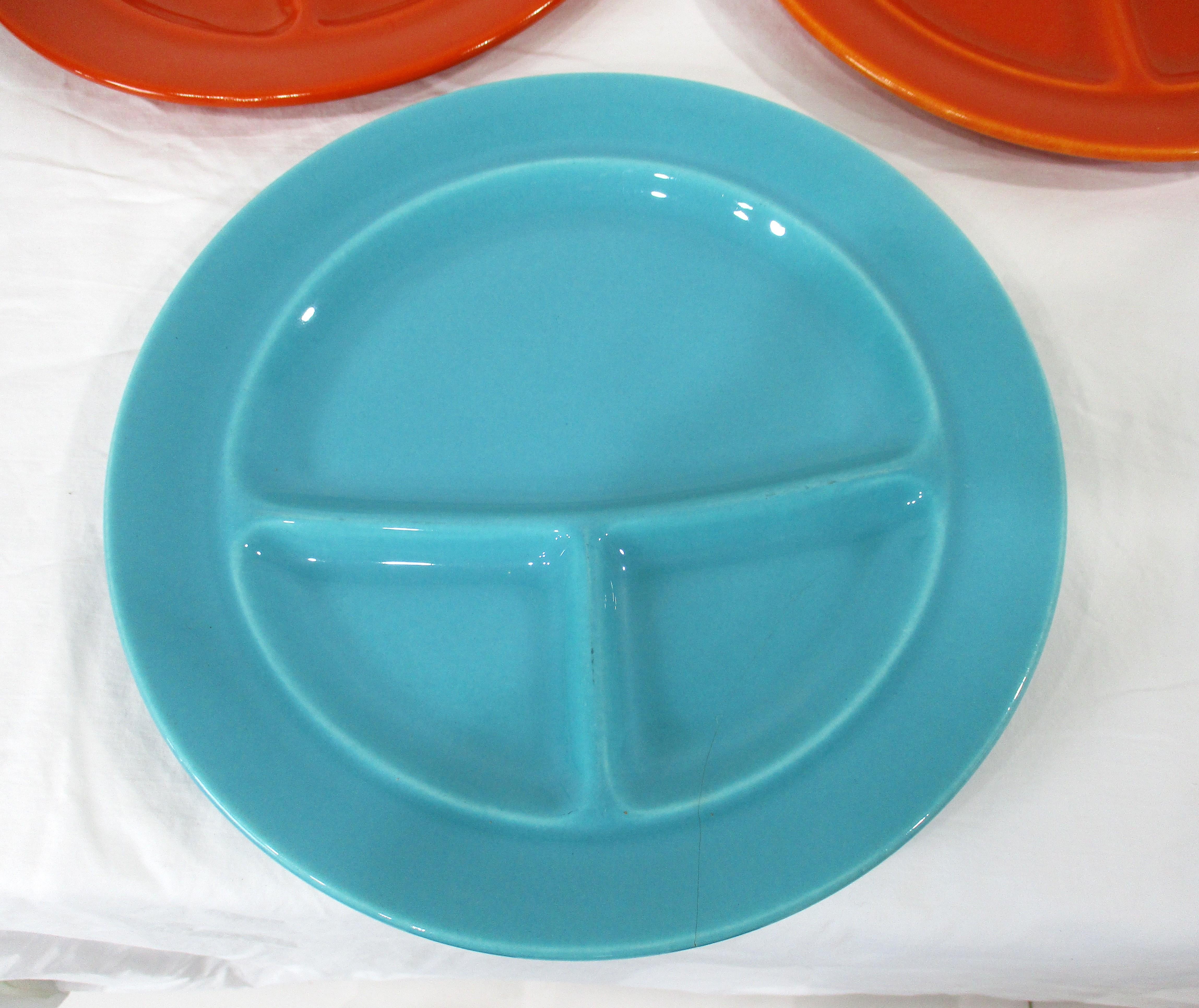 Un conjunto de cinco platos de cerámica de cena divididos o de parrilla , dos en azul y tres en un naranja brillante . Denominada California Pottery por su estilo y fabricada en el estado por la empresa Metlox Pottery . Una de las placas es una