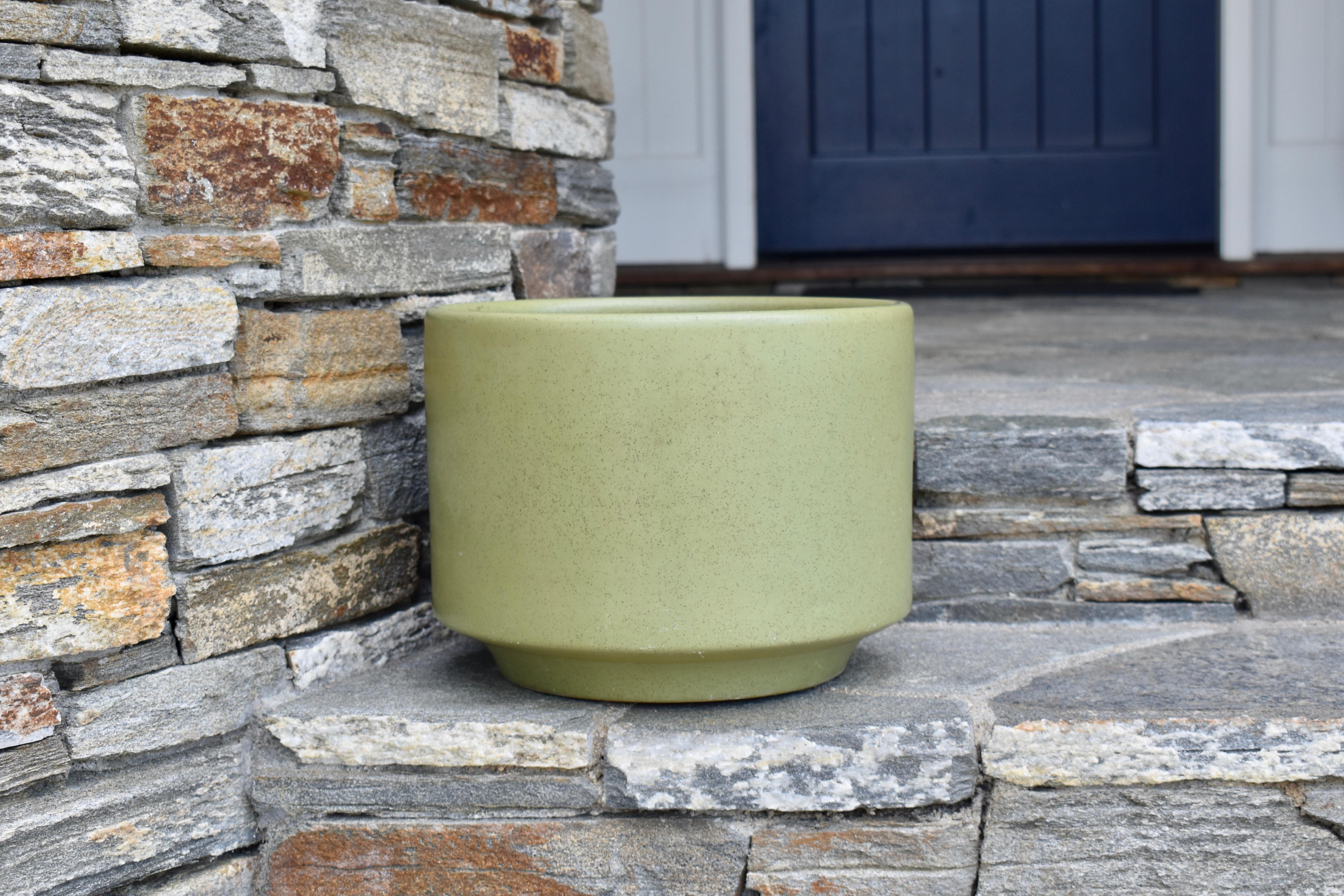 A smooth and matte light olive green-colored speckled California Pottery planter pot with USA marking on underside. Attributing to Gainey Pottery. No drain hole. Interior dimension is 10.63