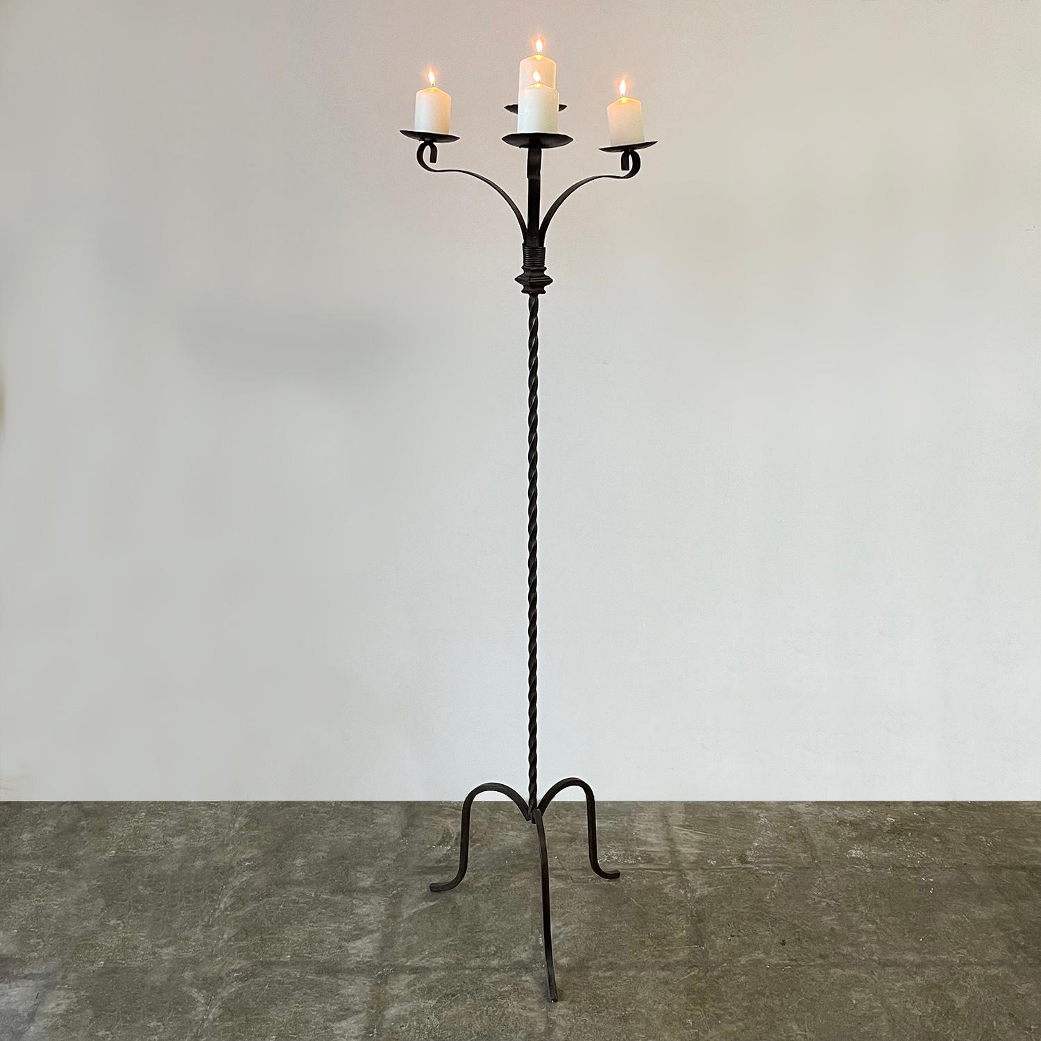 Spanish wrought iron torchiere standing candelabra
Early 20th century
Handcrafted rustic piece
Twisted wrought iron pillar supports four arms and floats on a high arched tripod base
Patina from age and use
Candles shown have a 4” diameter