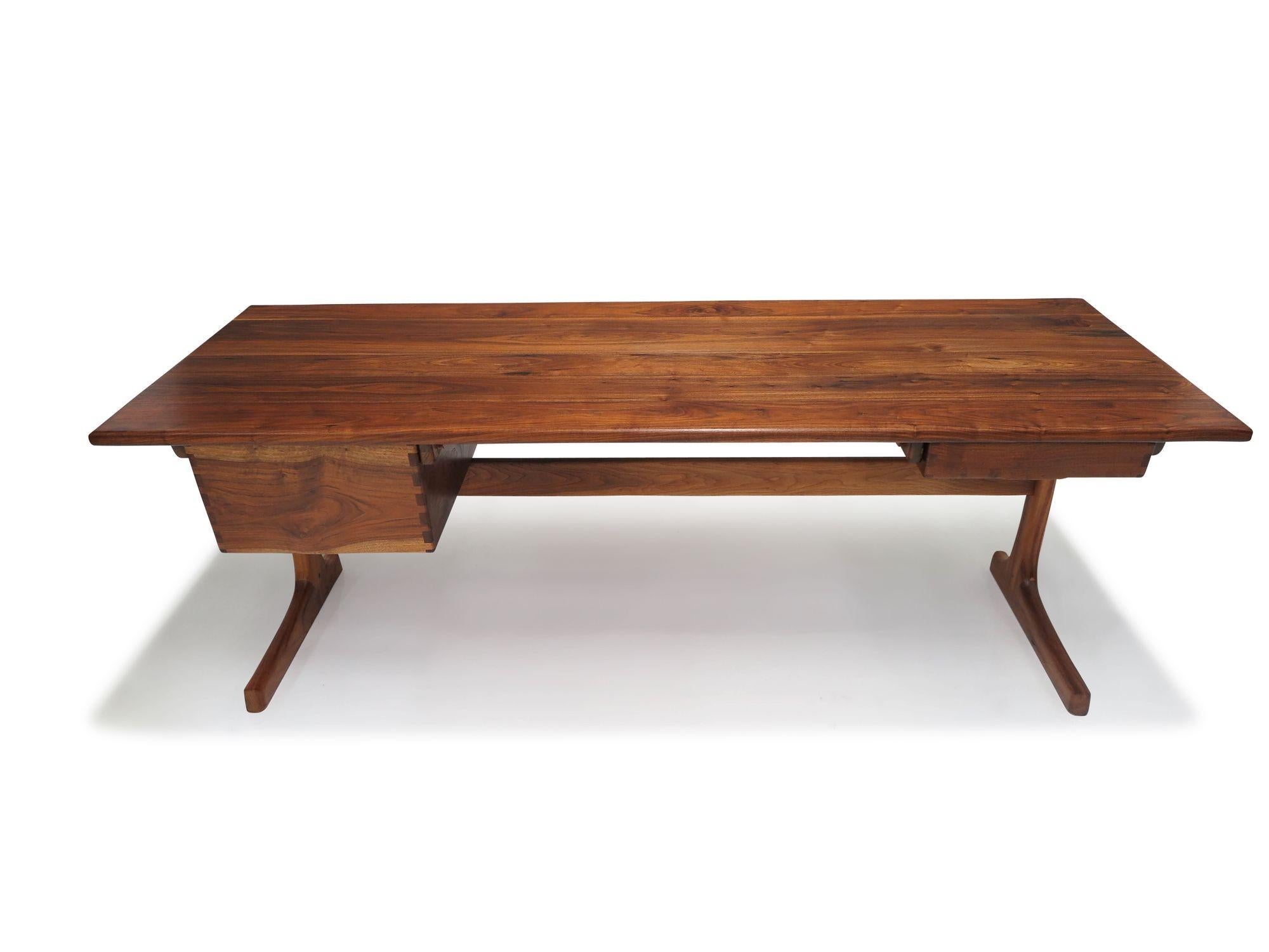 California studio desk by Berkeley craftsman, Jim Sweeney, handcrafted of solid black walnut. The desk features beautifully figured black walnut, two drawers with exposed joinery on sides, raised on sculptural pedestal base with cross stretcher. The