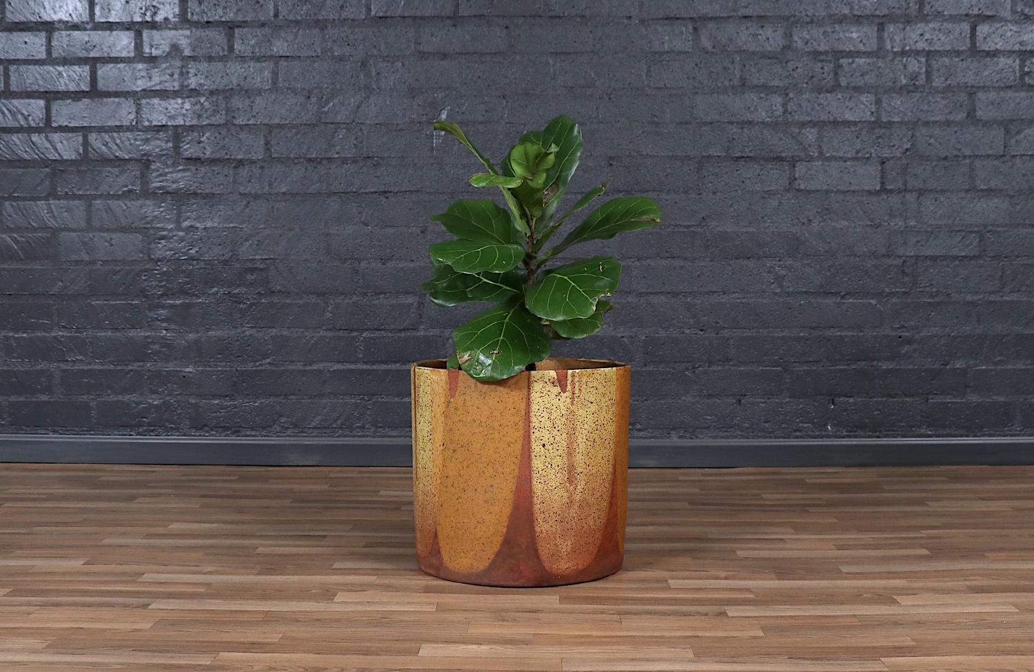 This exquisite flame-glazed ceramic planter by David Cressey and Robert Maxwell is a true testament to California modernism. Its rich, molten hues of deep amber, fiery orange, and earthy brown create a mesmerizing surface that feels both organic and