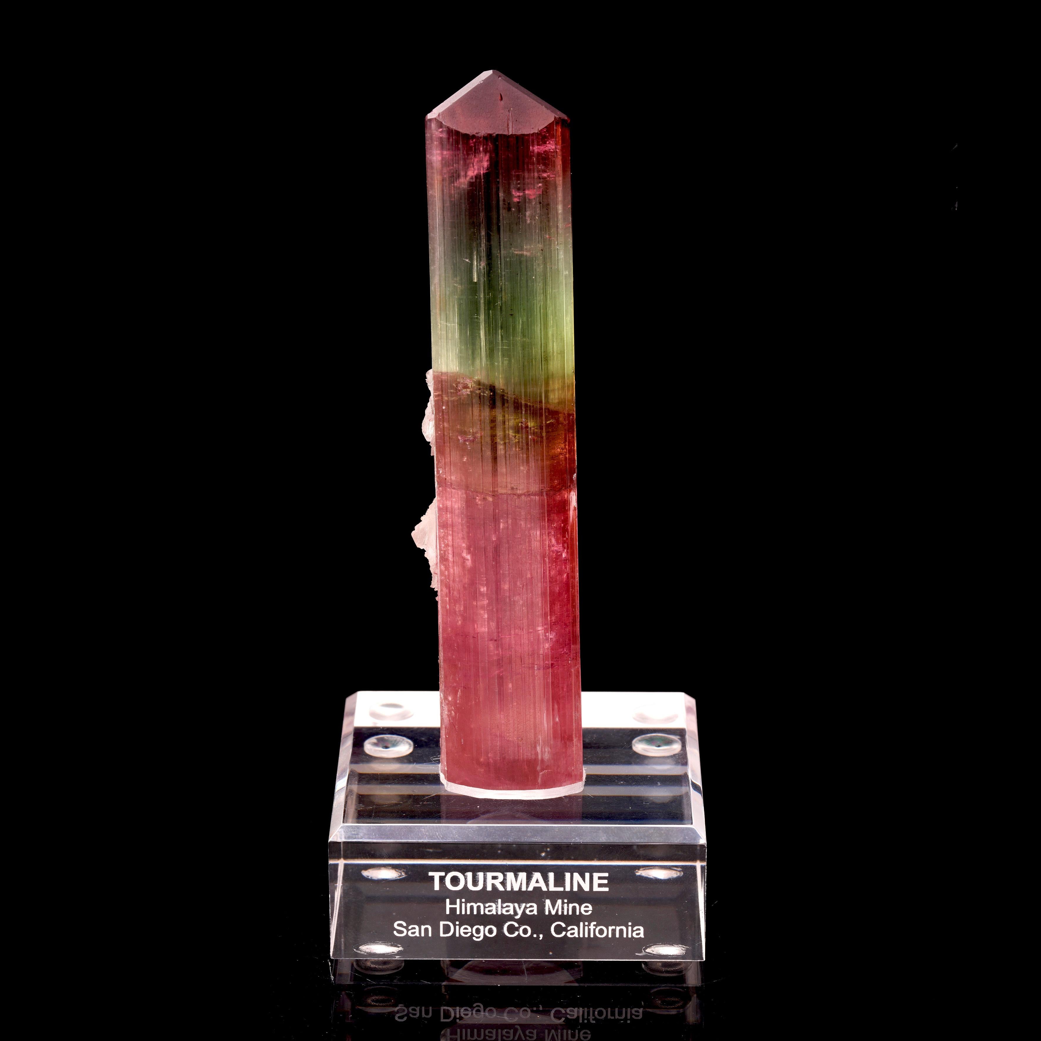 Experimenta la impresionante belleza de nuestra Turmalina Sandía, una pieza que capta a la perfección la vibrante esencia de la paleta de la naturaleza. Procedente de la ilustre Mina Himalaya de San Diego, California, este ejemplar de 15 cm de