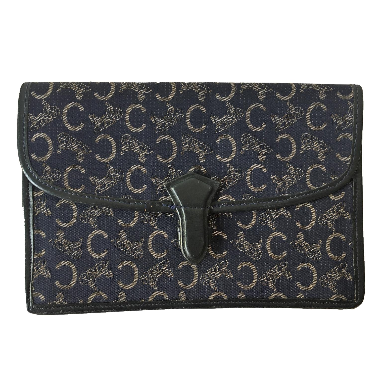 Pochette vintage Celine 1970 in tela con monogramma. Chiusura e finiture in pelle. Interno in pelle blu scuro con logo dorato. 4 scomparti interni e tasca applicata sul retro.
15 x 22 x 3 cm