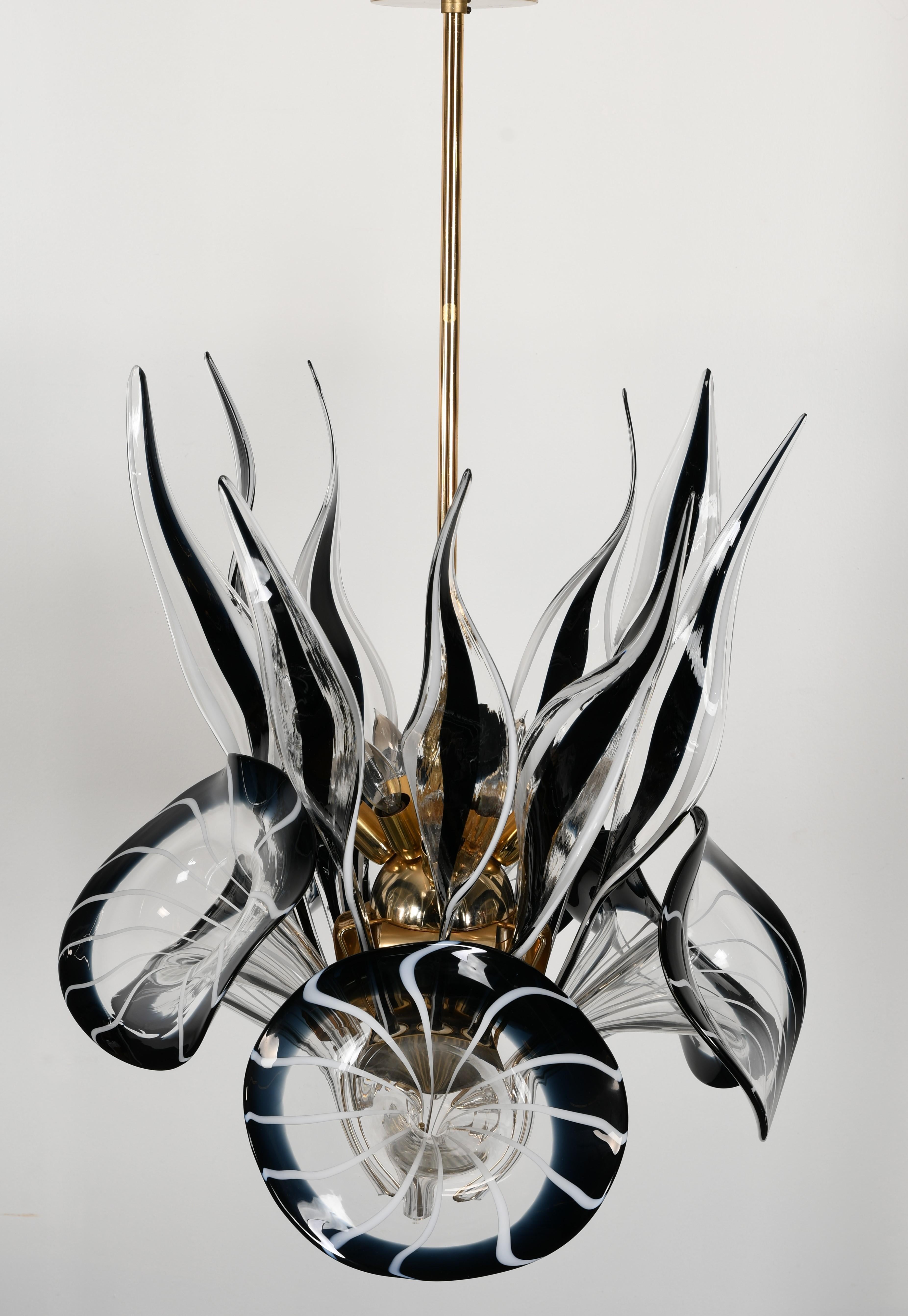 A fabulous calla lily chandelier in the manner of Franco Luce, 1970s. Five clear white and black Murano glass flowers with multiple glass leaves centered around a gold-plated brass armature. This chandelier has great scale and elegance and would