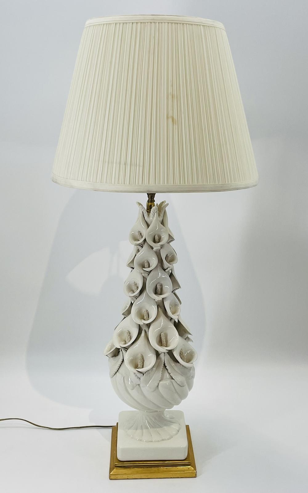 Introducing the exquisite Calla Lily Table Lamp, a timeless piece crafted by Bondia/Manises in Spain during the 1960's. 
This elegant lamp showcases a sleek white base adorned with a delicate flower design, exuding a touch of grace and