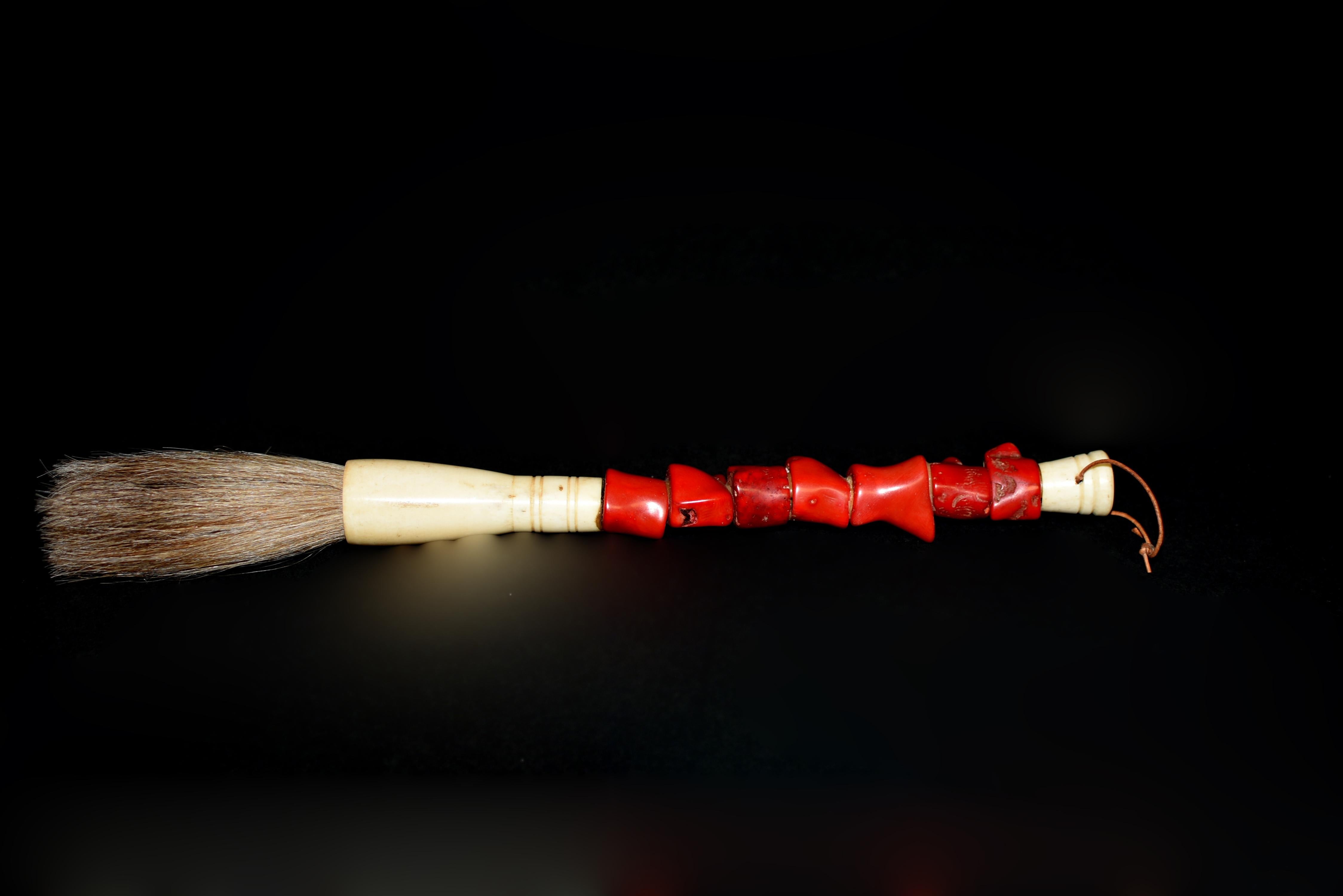 Dieser schöne, handgefertigte Pinsel bietet einen auffälligen Kontrast zwischen natürlichen und künstlerischen Elementen. Der Griff ist mit leuchtend roten Korallenimitaten verziert, von denen jedes einzelne sorgfältig geformt und platziert wurde,