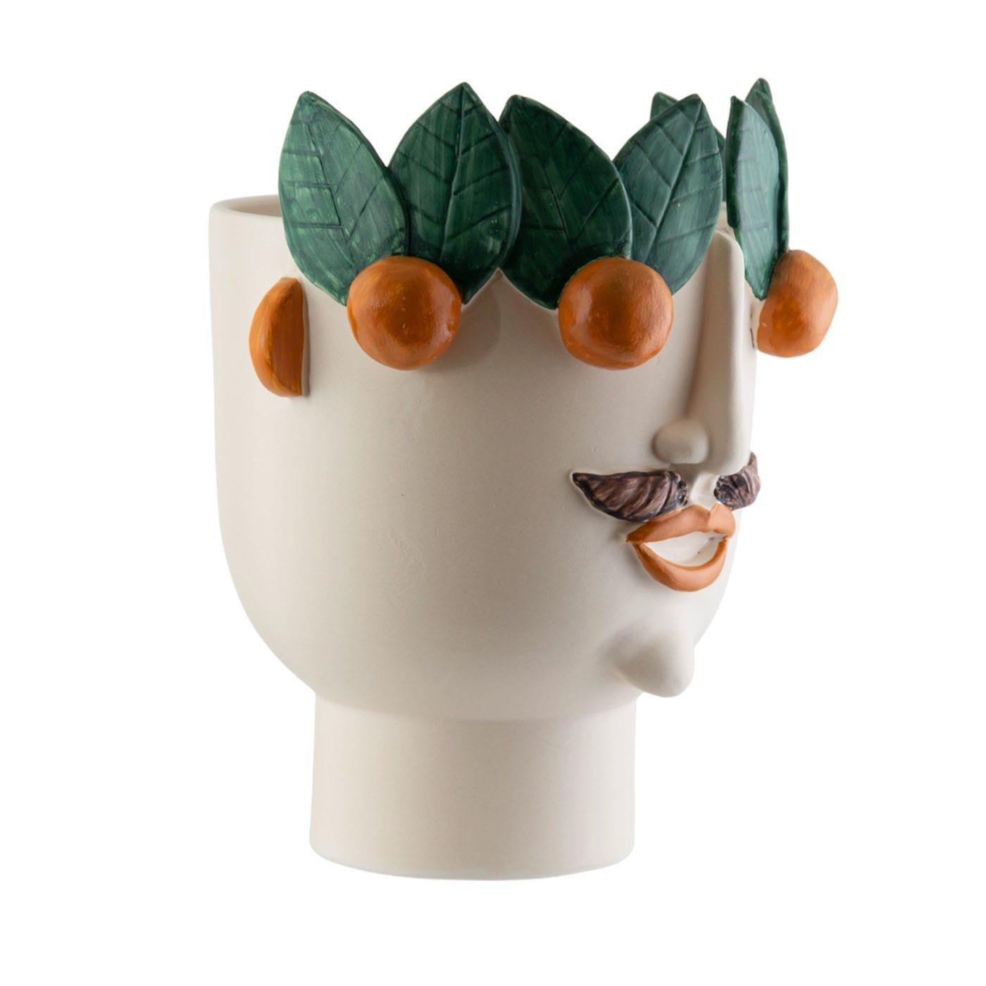 La seconde tête en céramique cuite au feu, fabriquée à la main avec des reliefs de visages et de mandarines, peut être utilisée pour tenir des plantes, des fleurs et parfois même des bouteilles avec de la glace. Calogero vend des mandarines au