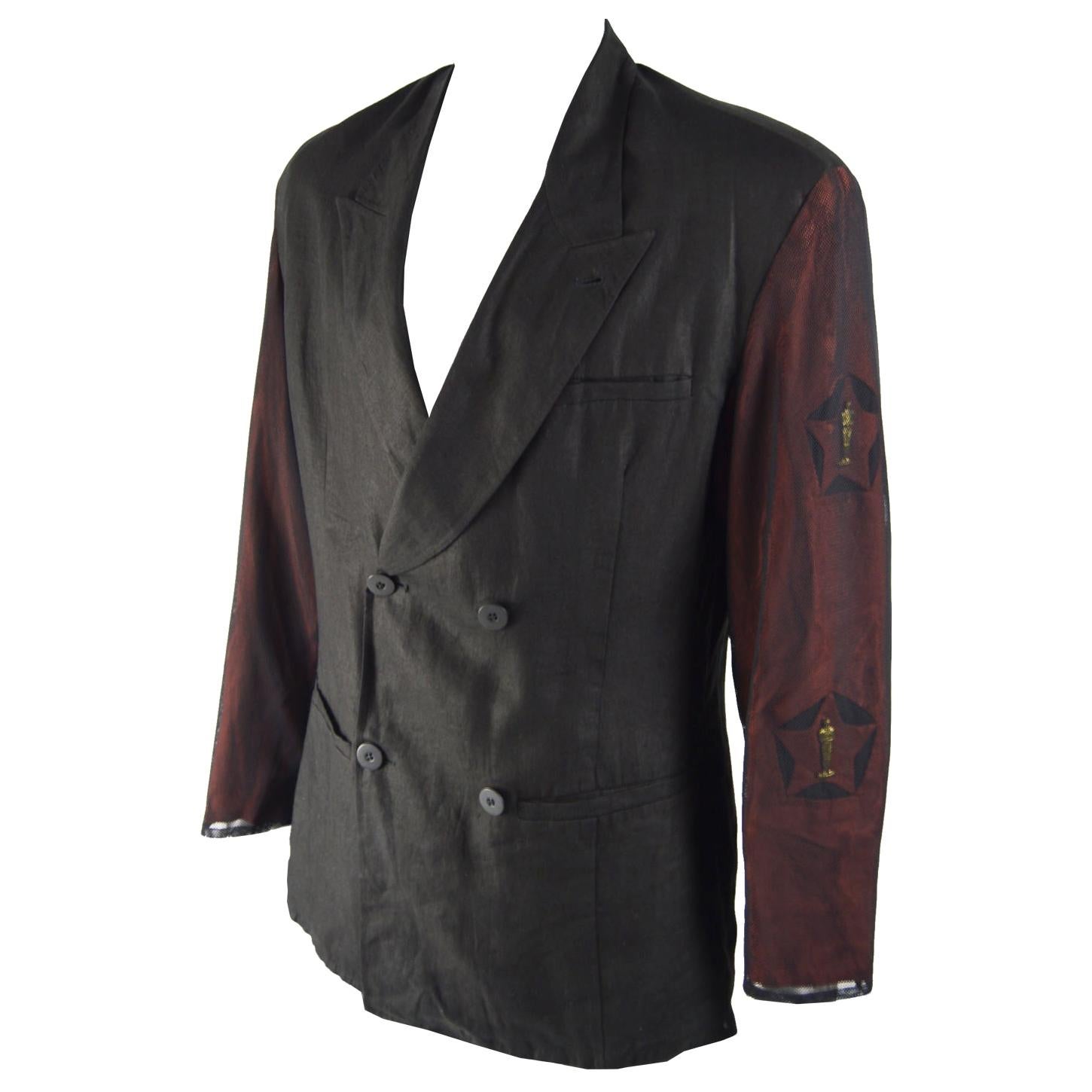 An amazing and ultra rare vintage mens blazer jacket from the 80s by genius Italian fashion designer duo, Calugi e Giannelli. In a black linen with red cut out sleeves that are embellished with Oscar statues and then covered in mesh for a