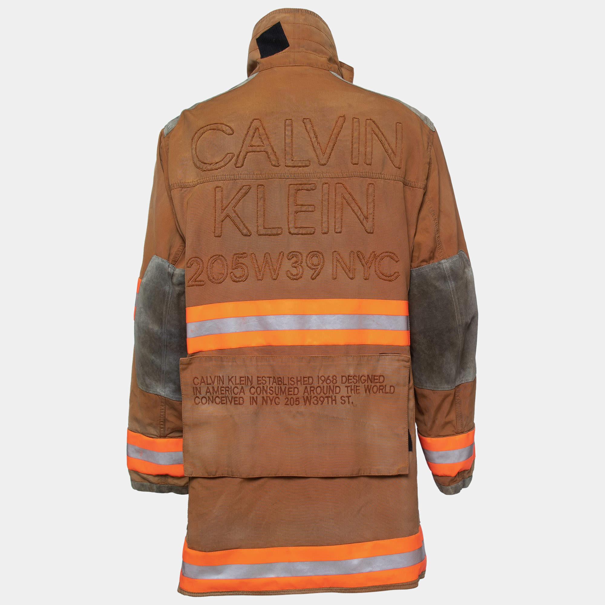 The Calvin Klein jacket is a rugged yet stylish outerwear piece. Crafted from distressed brown cotton, it features a fireman-style design with reflective accents for added safety. This jacket combines fashion with functionality, making it suitable