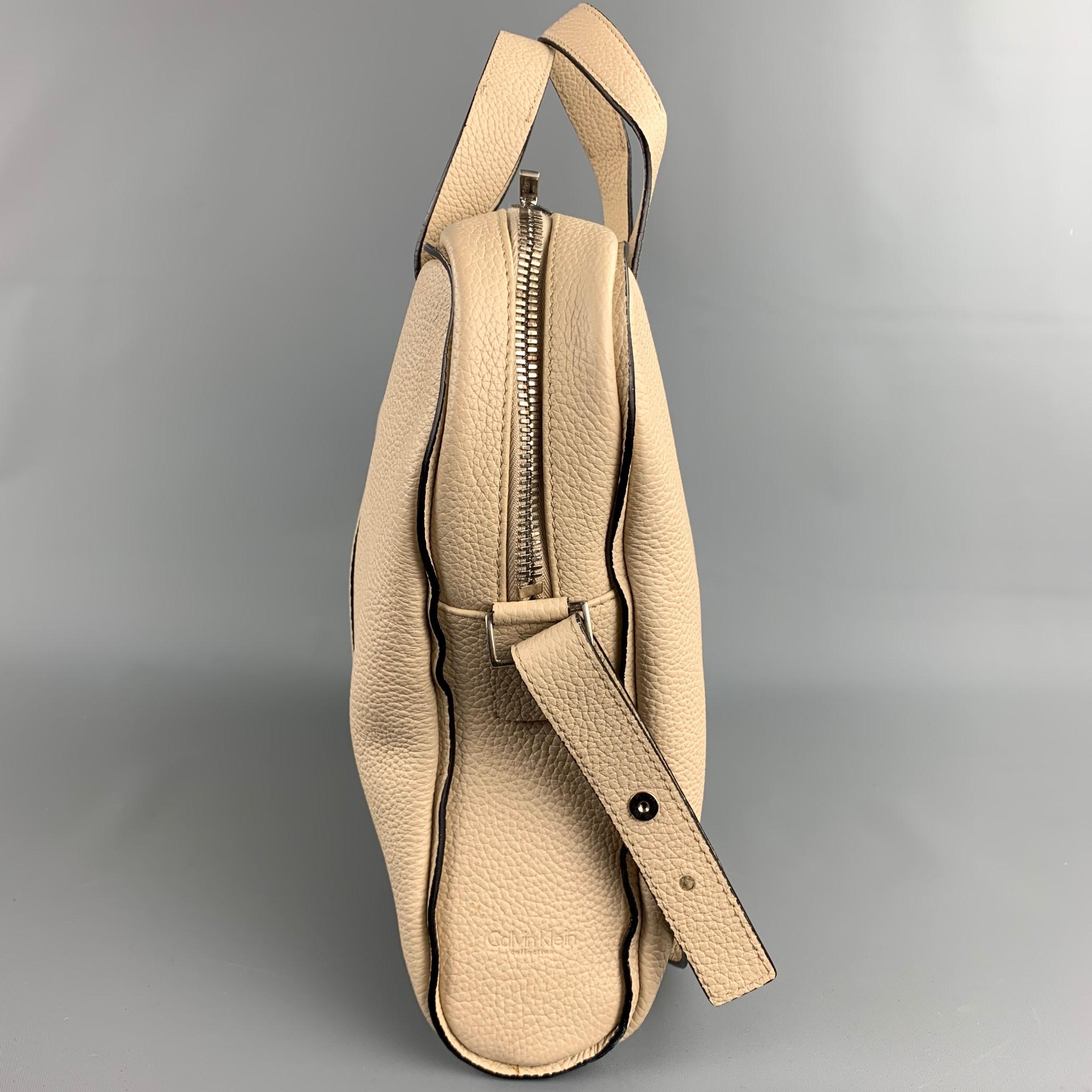 CALVIN KLEIN COLLECTION handbag comes in a beige pebble grain leather featuring a adjustable cross body strap, top handles, inner slots, and a zipper closure.

Very Good Pre-Owned Condition.

Measurements:

Length: 15 in.
Width: 3 in.
Height: 11.5