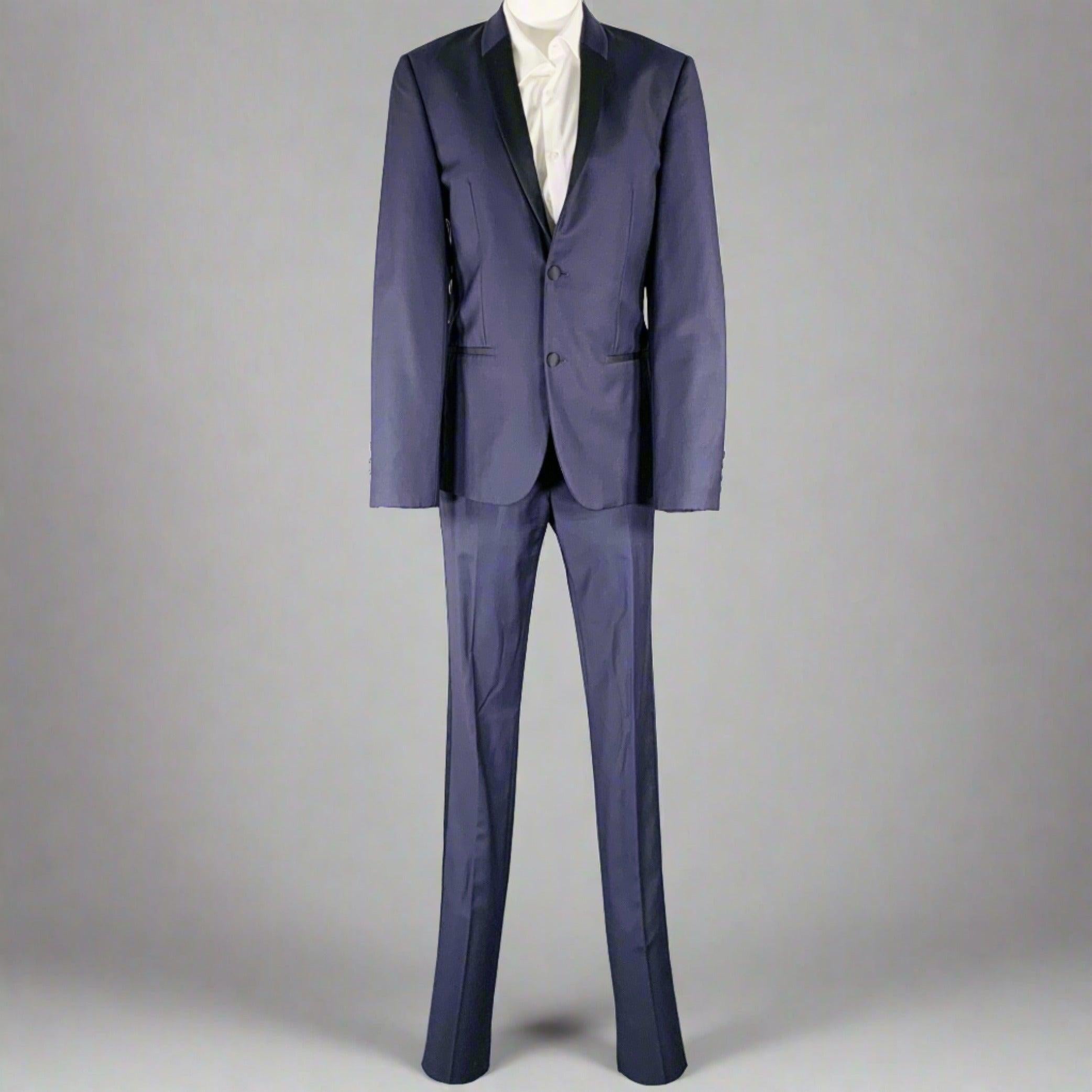 Lo smoking di Calvin Klein Collection è in lana blu e blu con fodera integrale e comprende un cappotto sportivo monopetto a due bottoni con rever a scialle e pantaloni piatti abbinati. Made in Czech Republic.Very Good Pre-Owned Condition. Moderati