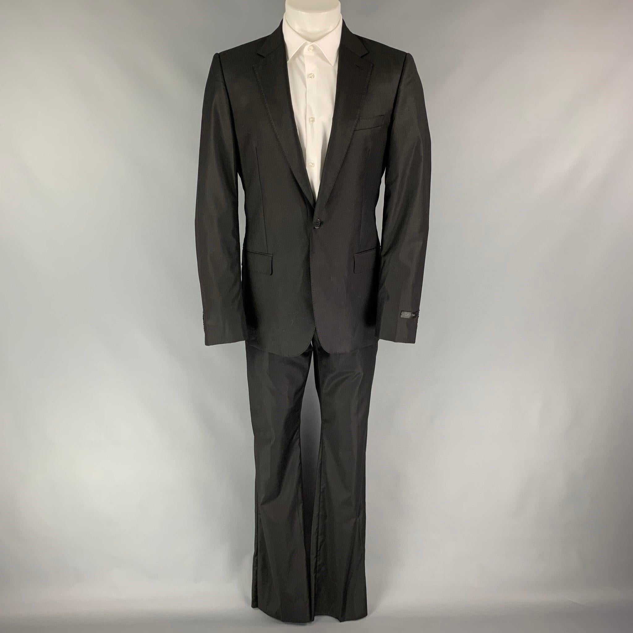 CALVIN KLEIN COLLECTION
 suit comes in a black wool with a full liner and includes a single breasted, single button sport coat with a notch lapel and matching flat front trousers. Excellent Pre-Owned Condition. 
 

 Marked:  48/38 
 

 Measurements: