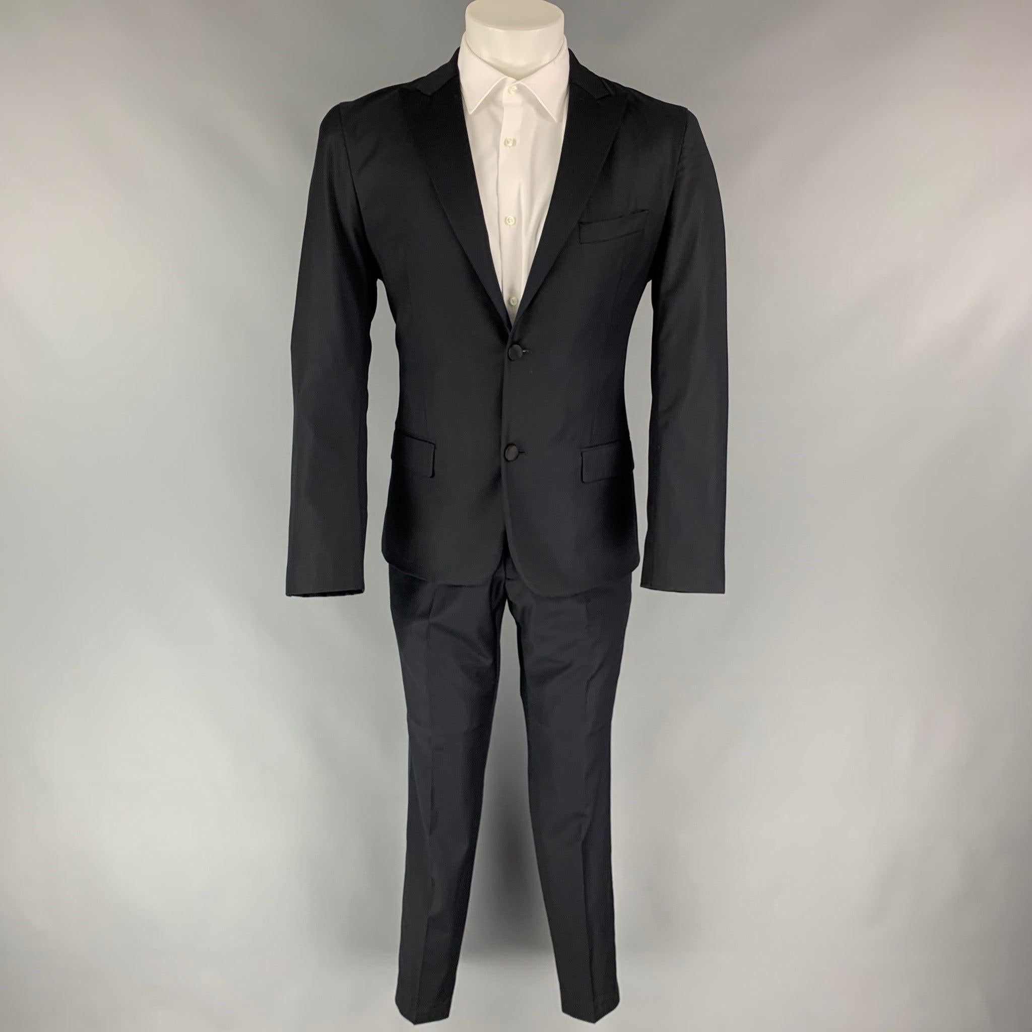CALVIN KLEIN COLLECTION tuxedo suit comes in a black wool with a full liner and includes a single breasted, two button sport coat with a peak lapel and matching flat front trousers. Very Good Pre-Owned Condition. 
 

 Marked:  48/38 
 

