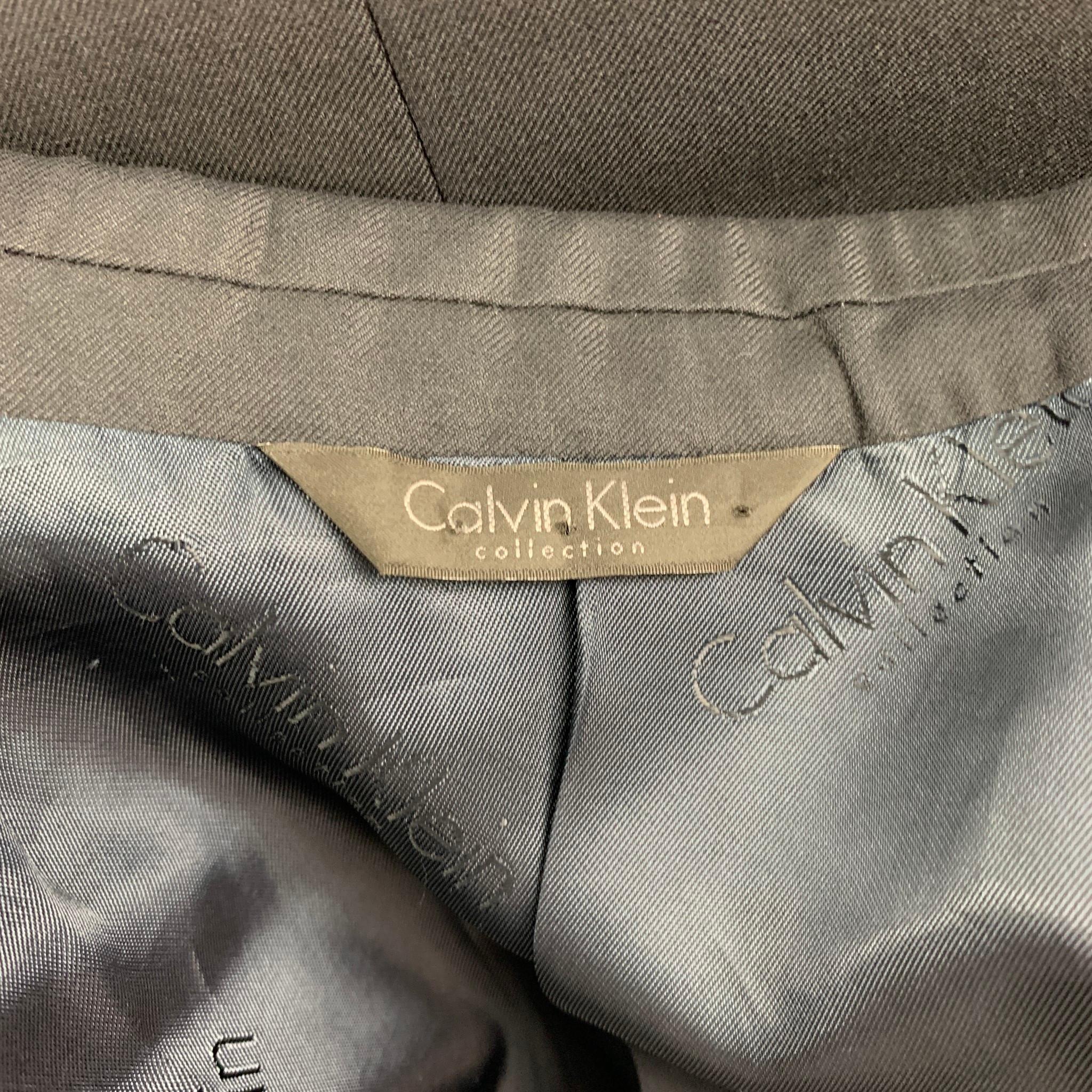 CALVIN KLEIN COLLECTION sport coat comes in a navy wool with a full liner featuring a peak lapel, flap pockets, and a double button closure.

Very Good Pre-Owned Condition.
Marked: 40/50

Measurements:

Shoulder: 18 in.
Chest: 40 in.
Sleeve: 26