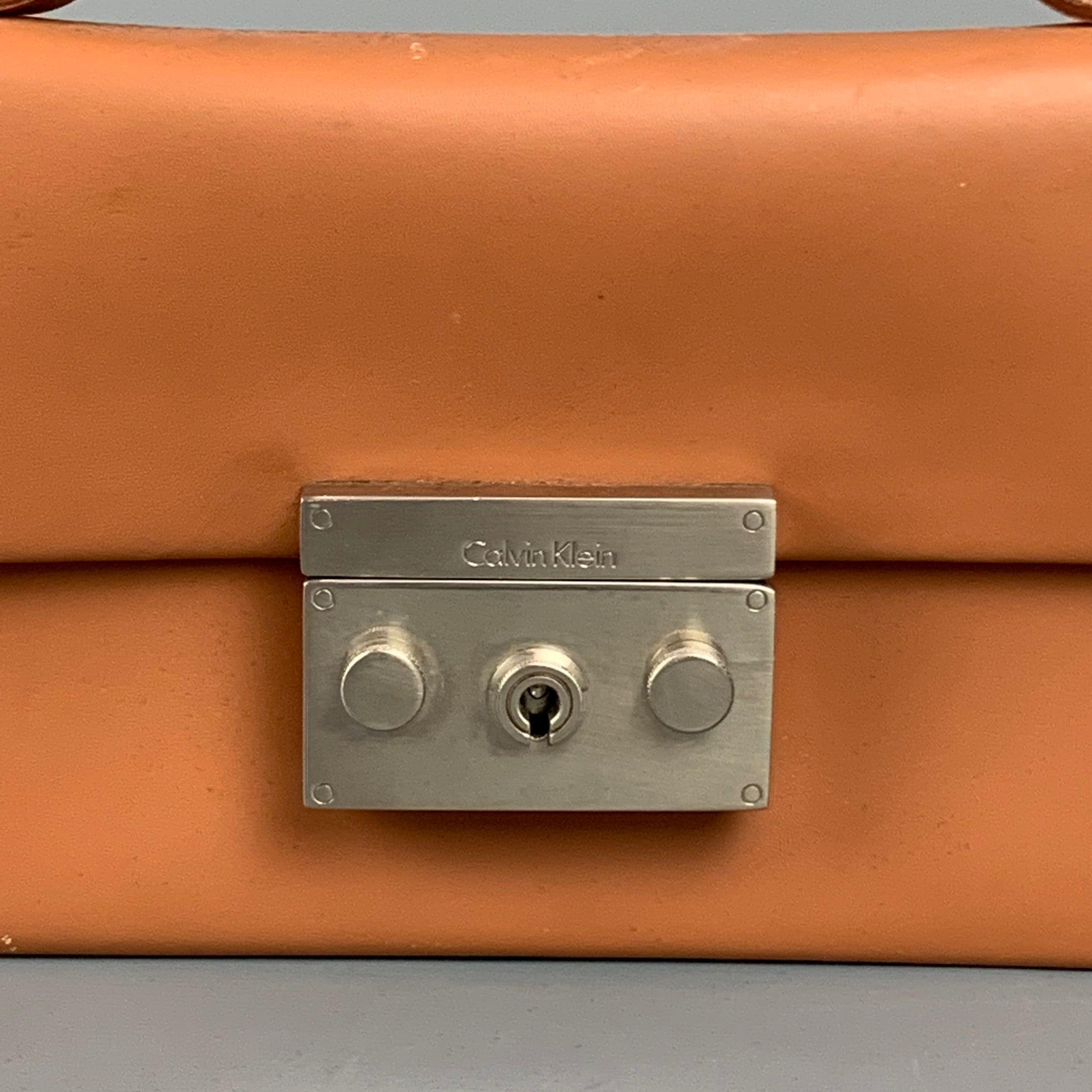 CALVIN KLEIN COLLECTION mini bag comes in a tan leather featuring a top handle, multiple slots, and a key lock closure. Comes with keys. Made in Italy.Very Good
 Pre-Owned Condition. 
 

 Measurements: 
  Length: 7 inches Width: 1 inches Height: 4.5