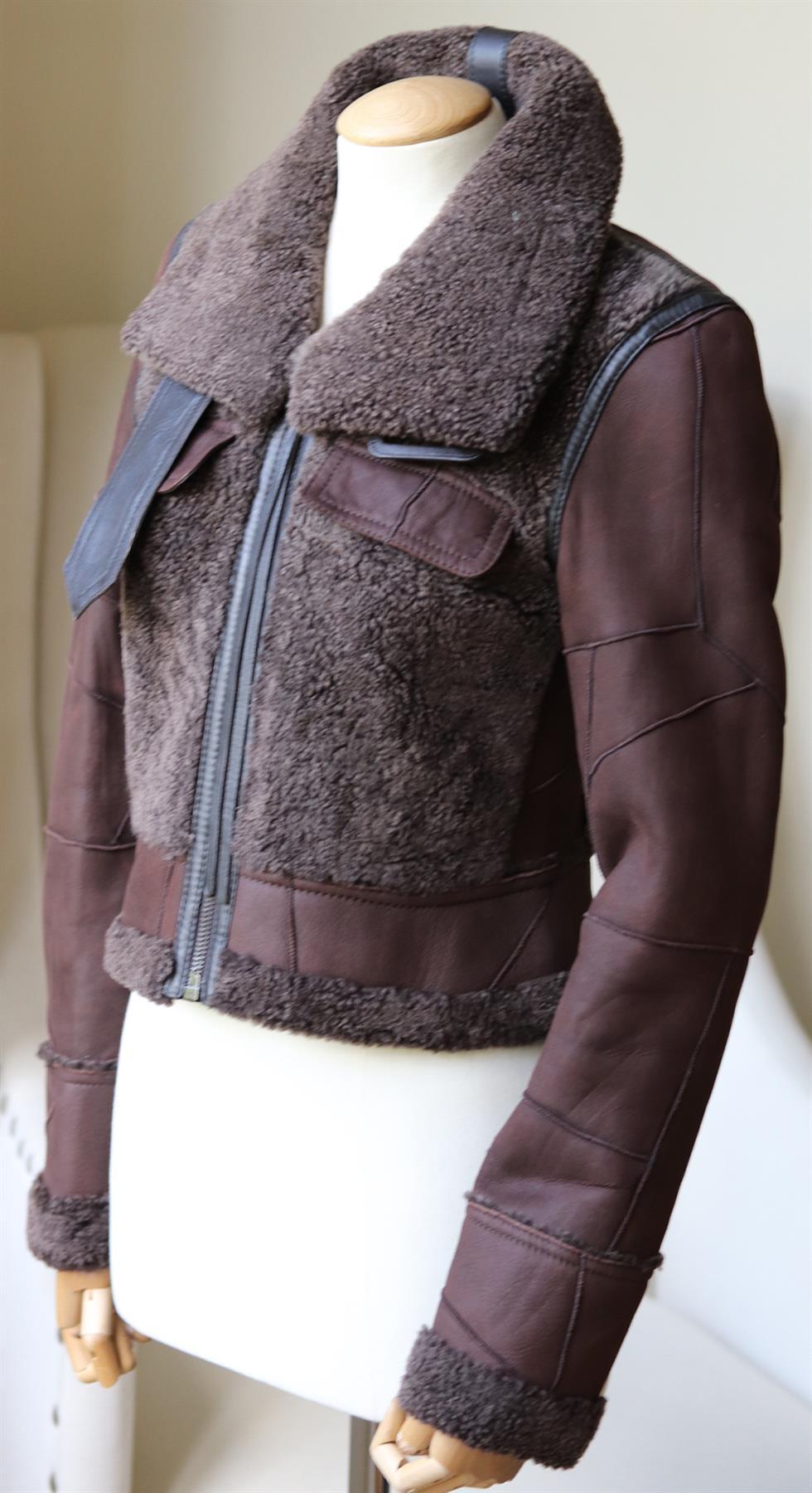 This Calvin Klein Collection jacket has been made from brown shearling, its has smooth leather buckle fastening at the neck and a cropped slim-fit.
Brown shearling, brown leather. 
Zip fastening along front. 
100% Shearling (Lamb).

Size: IT 38 (UK