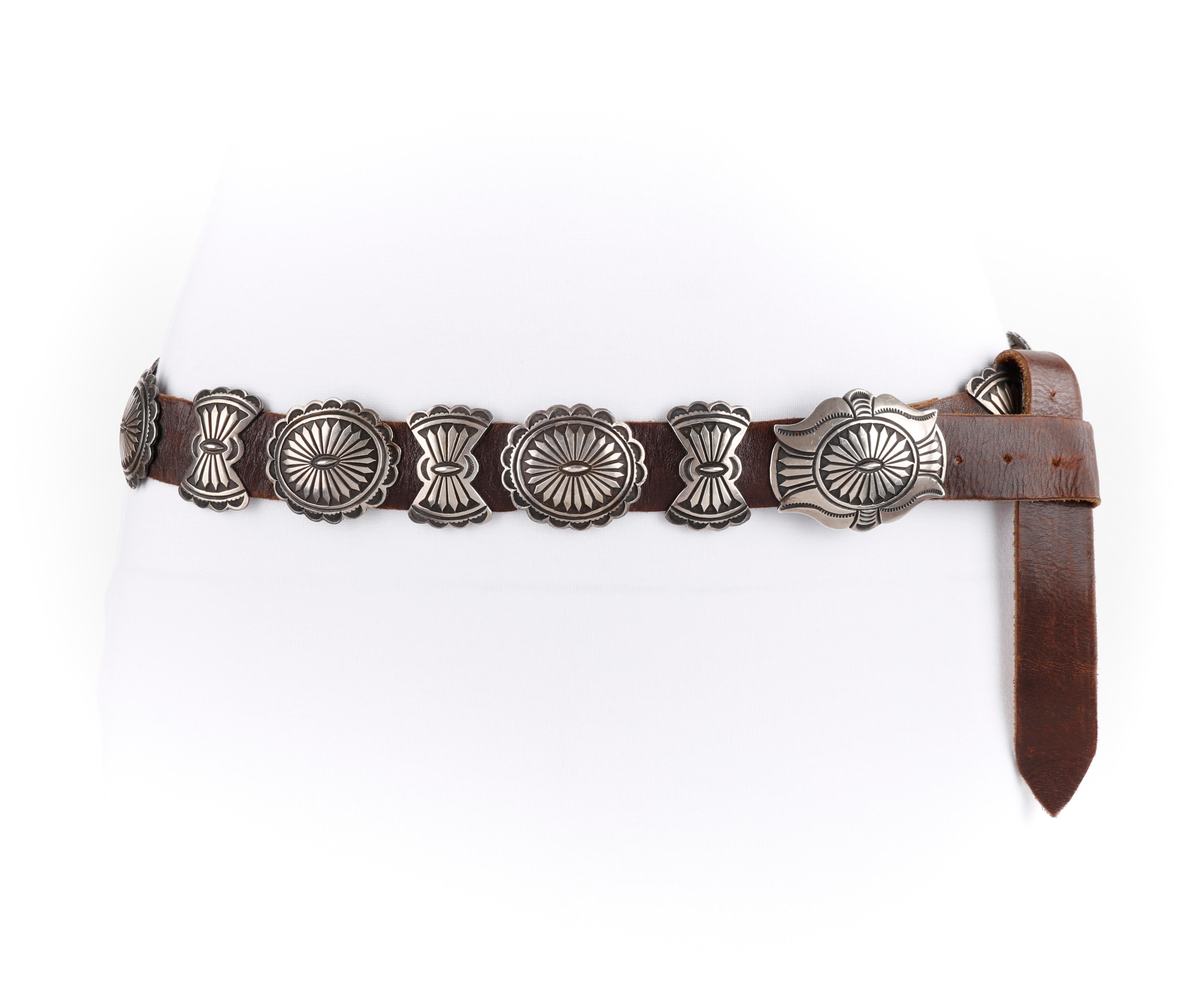 CALVIN MARTINEZ c.1980s Sterling Silver Handmade Traditional Navajo Concho Belt
 
Circa: 1980’s 
Label(s): C. MTZ
Designer: Calvin Martinez
Style: Concho belt
Color(s): Shades of russet brown (belt); silver (conchos)
Marked Fabric Content: Sterling