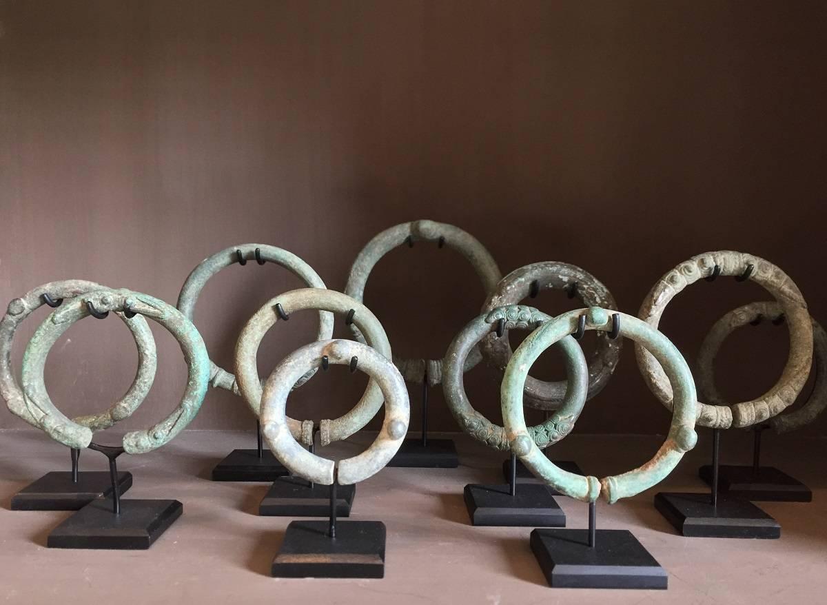A collection of 11 bronze Cambodia bronze bracelets mounted on custom-made stands. These bracelets were skilfully and elegantly shaped by the ancient Khmer culture between the 8th and 13th century AD. As a art object they come across as almost
