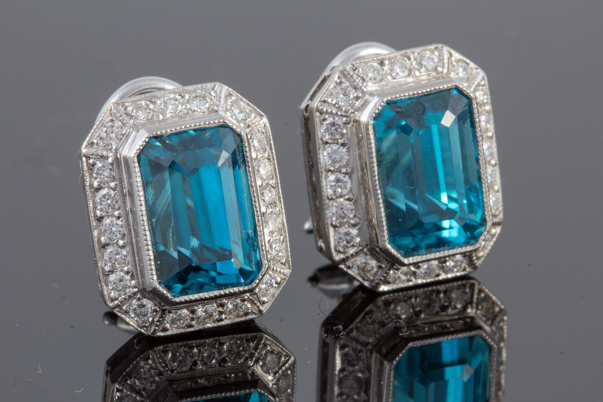 These exquisite earrings feature exceptionally clean emerald cut blue zircons weighing 10.34 carats.  Surrounded by .52 carats of round brilliant  F/G VSI diamonds, the hand crafted bezels are platinum.   Measuring approx. 14mm x 12mm, these