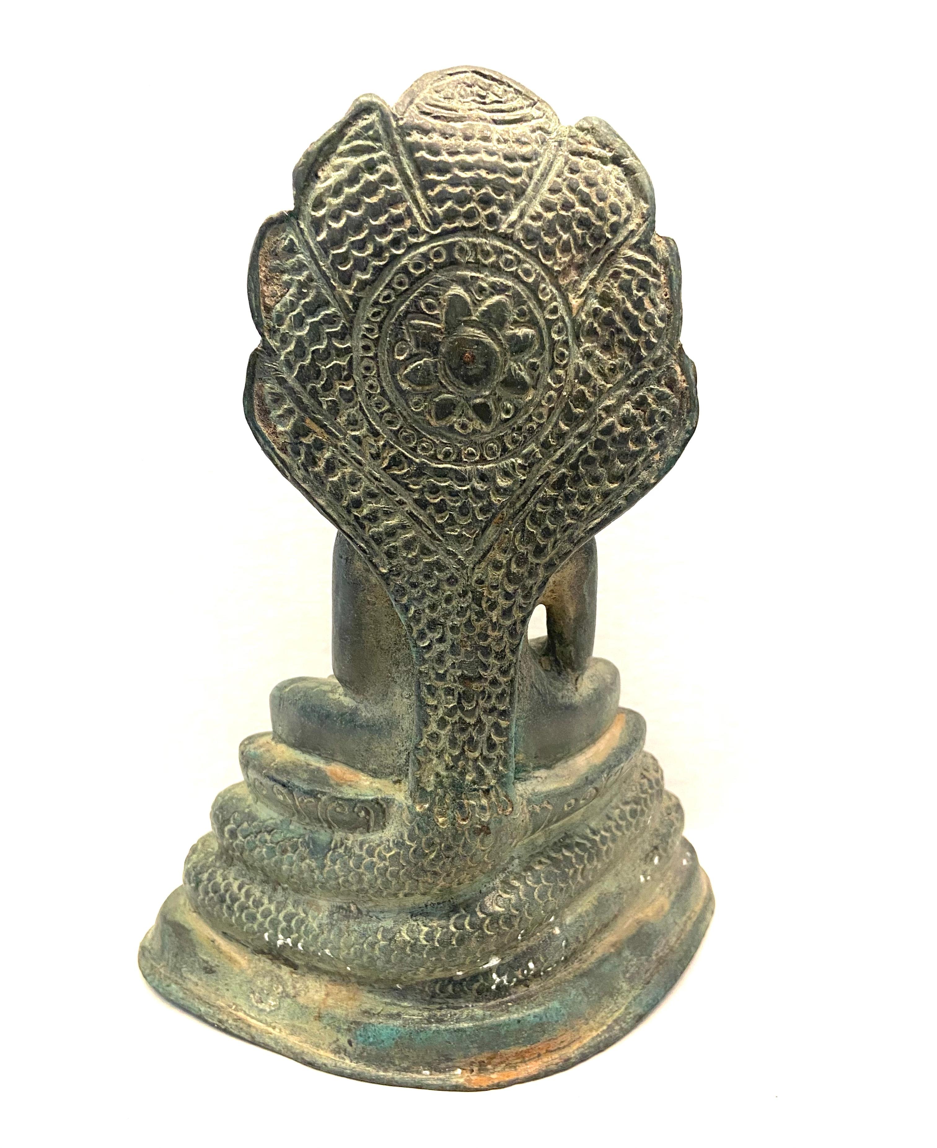 This Cambodian bronze Naga Buddha has been hand-cast. The Naga primarily represents rebirth, and mortality. The cult of the animistic Naga (Cobra) is an ancient practice in India and was readily taken up in Cambodia. Sitting in meditation on four