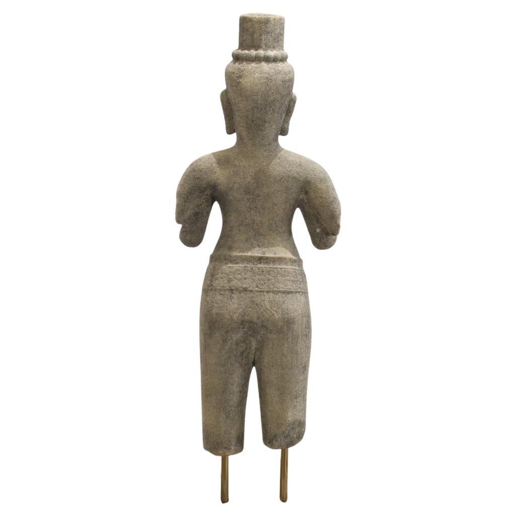 Questo straordinario pezzo presenta una statua cambogiana in pietra, una potente testimonianza dell'antica arte, elevata a nuove vette scultoree. La figura in pietra, con la sua espressione serena e i suoi dettagli ammorbiditi dal tempo, possiede