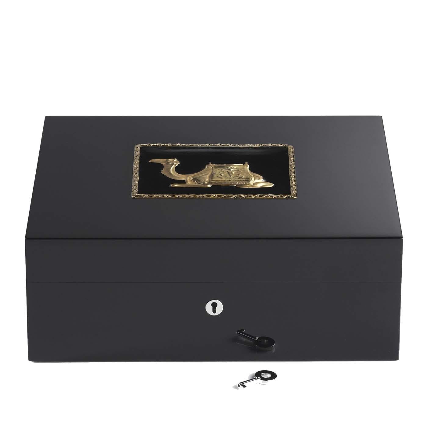 Containing up to 75 cigars, this exclusive wooden humidor showcases a golden reproduction of a camel gracing its lid, framed by edges in the same bright finish. The black background of the decoration matches the black wooden structure of this