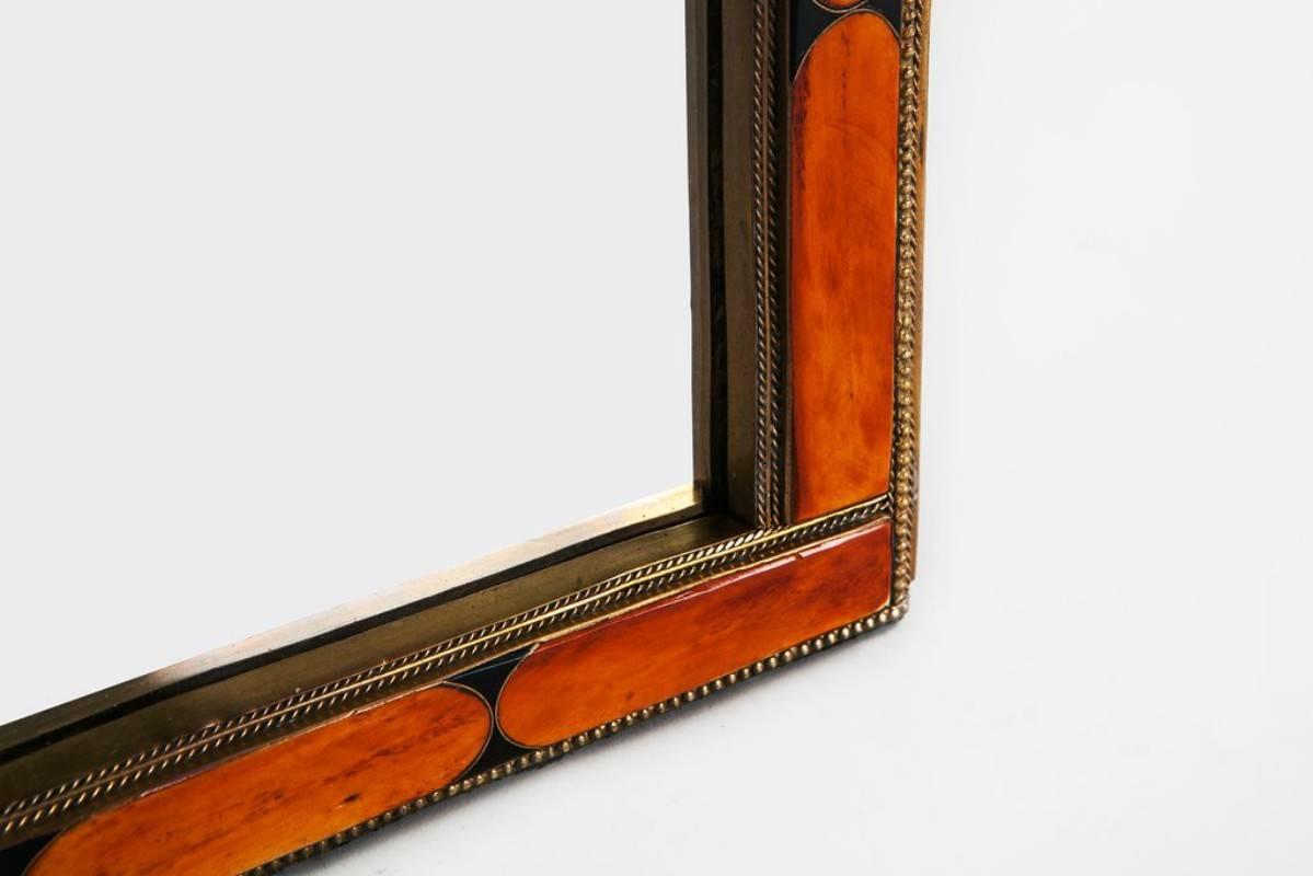 Come delight in the warm tones of this uniquely constructed small-size mirror. With generous pieces of orange camel bone set into a frame of brass, this mirror exudes a muted, fiery glow. HSX.




 