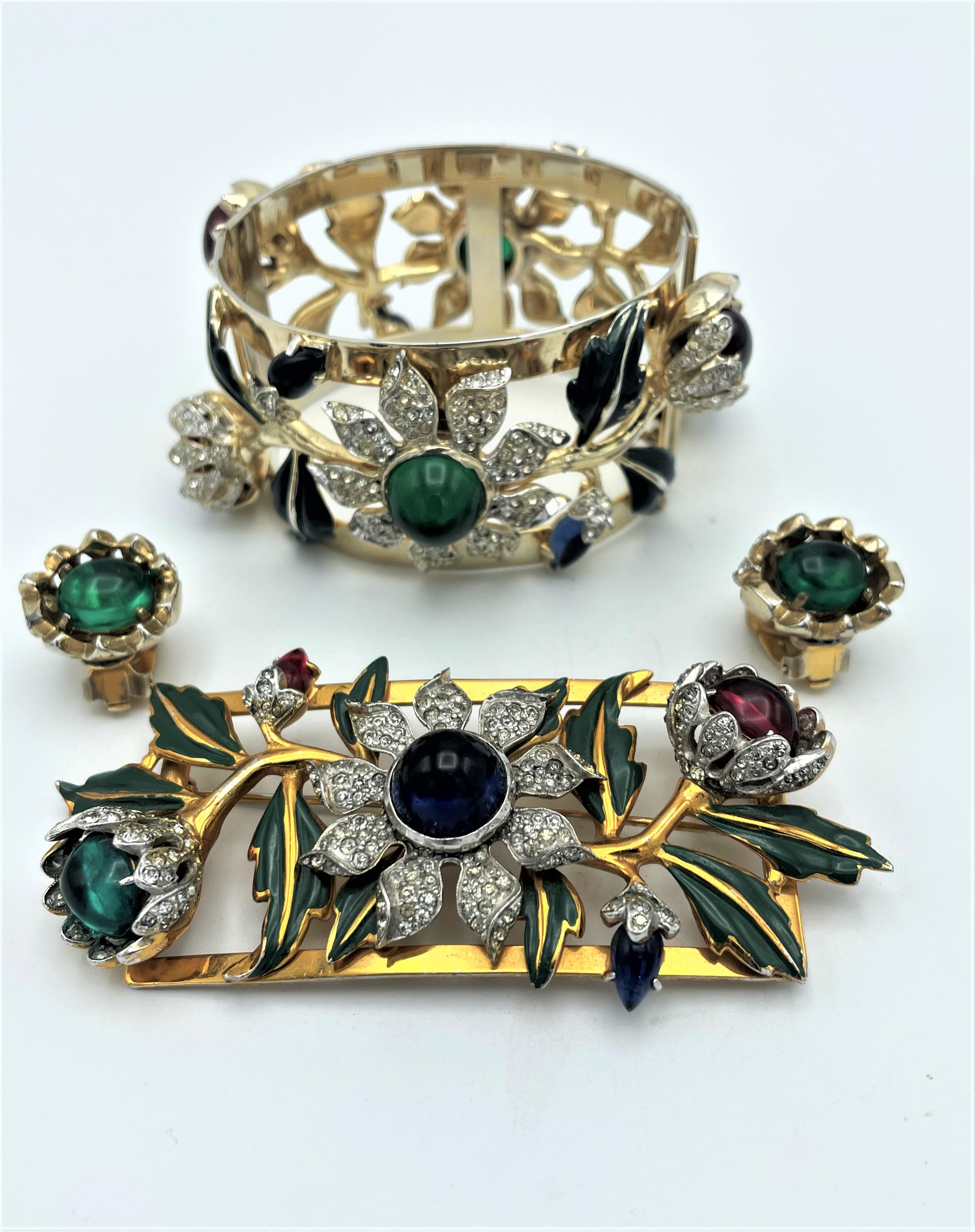 À propos de
Bracelet, broche et boucle d'oreille vintage Camelia par Corocraft  Design/One 1939 USA avec cabochon vert et rouge, feuilles émaillées vertes et nombreux strass. 
Mesures  Bracelet large de 1,58 pouces (4 cm) de diamètre  2,66 pouces