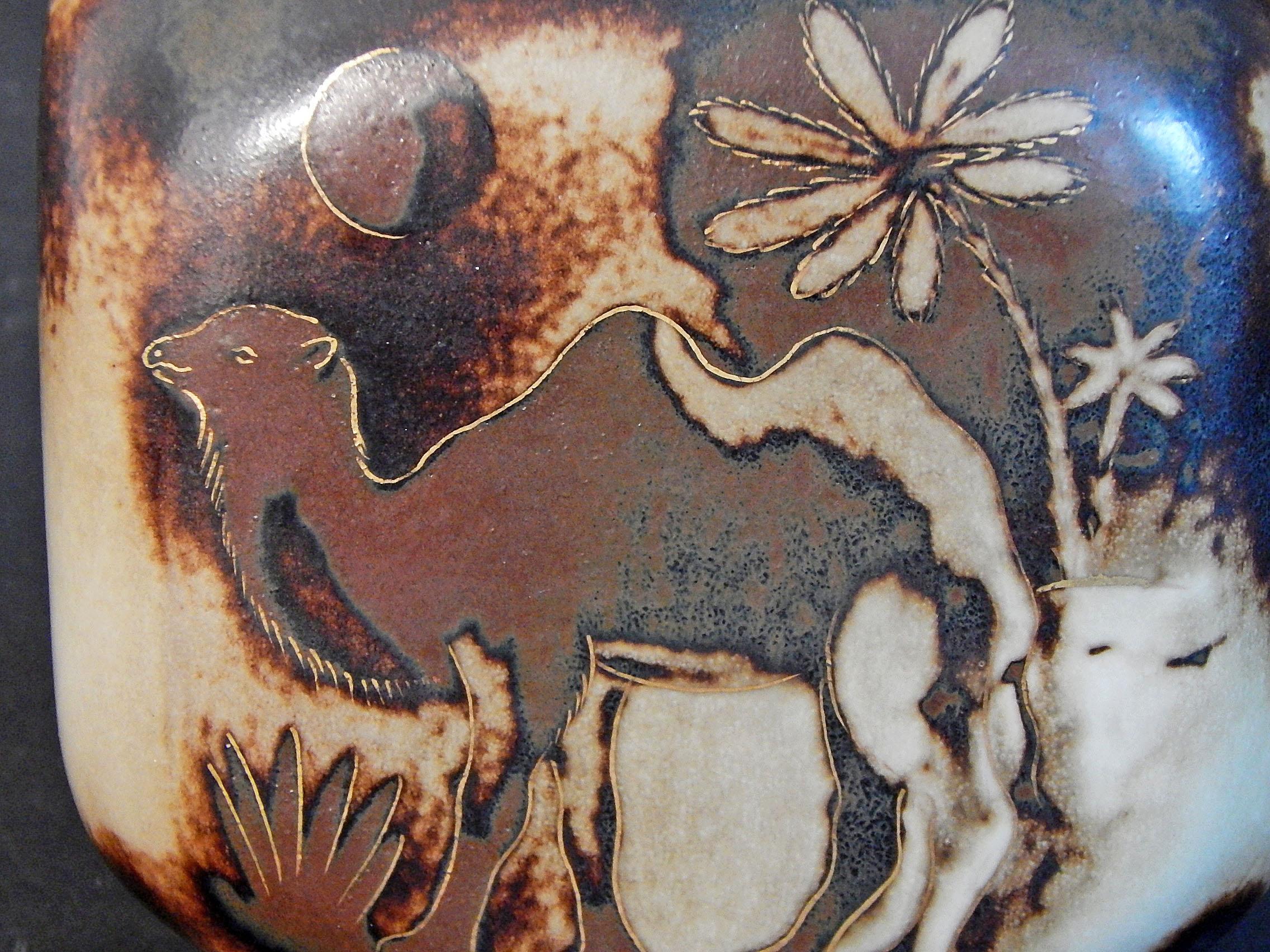 Beautifully glazed in shades of brown, ivory and gold, this striking vase depicts bactrian, two-hump camels flanked by palm trees, in a lovely moonlit night. This piece was designed by Gunnar Nylund for Rorstrand pottery in Sweden. Before he became