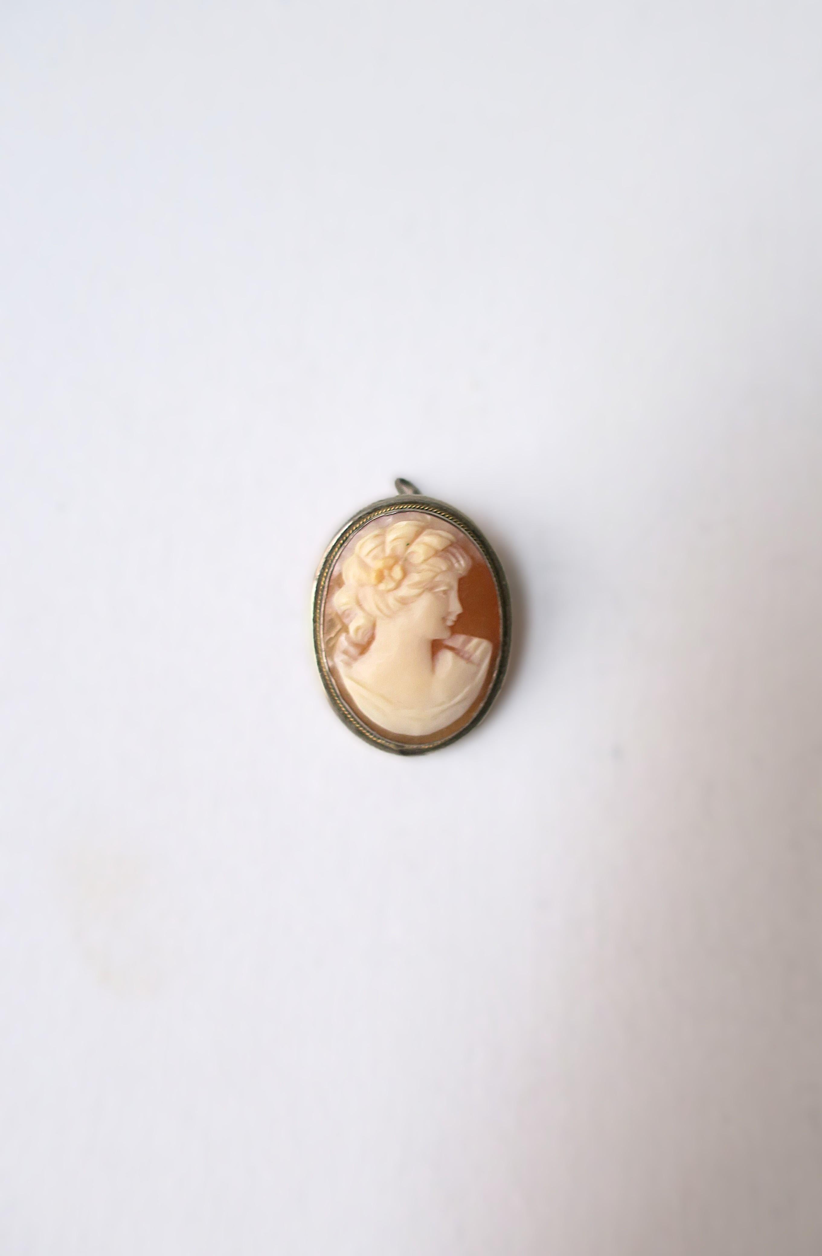 A beautiful shell cameo pendant and brooch set in silver with twisted gold rope accent, circa late-19th century to early-20th century. Piece is two in one; wear as a brooch or as a pendant on a chain link necklace (chain necklace for photo-op only);