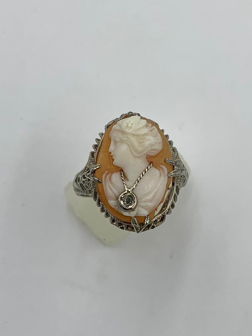 A SUPERB VICTORIAN - BELLE EPOQUE CARVED SHELL CAMEO DIAMOND HABILLE RING WITH A GORGEOUS FACE AND ABSOLUTELY MAGNIFICENT DETAIL AND ARTISANSHIP IN A BEAUTIFUL AND ELEGANT 14 KARAT WHITE GOLD FILIGREE SETTING.  She is wearing a beautiful diamond