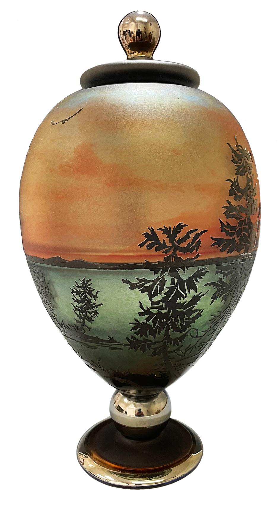 This cameo etched lidded jar by Gary Genetti is incalmo and overlay blown glass. The original artwork is drawn, hand cut then pressure etched through layers of color to create the imagery. The piece consists of sections of layered colored glass