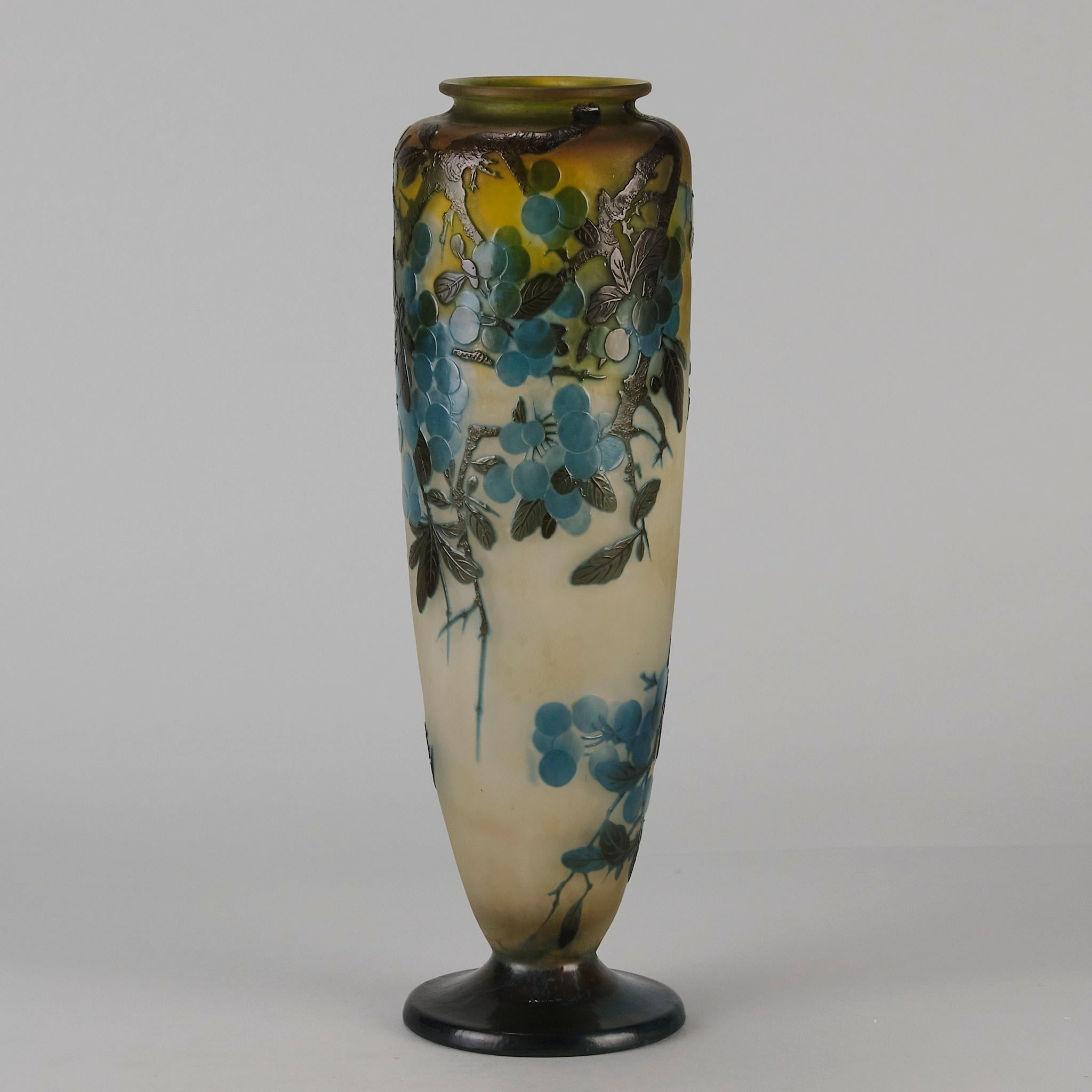 Vase en verre camée du début du 20e siècle, taillé à l'acide et gravé d'une branche d'arbre fruitier fleurie de prunelles bleu électrique sur un fond crème/jaune pâle. La surface est très finement finie à la main et la couleur est excellente, signée