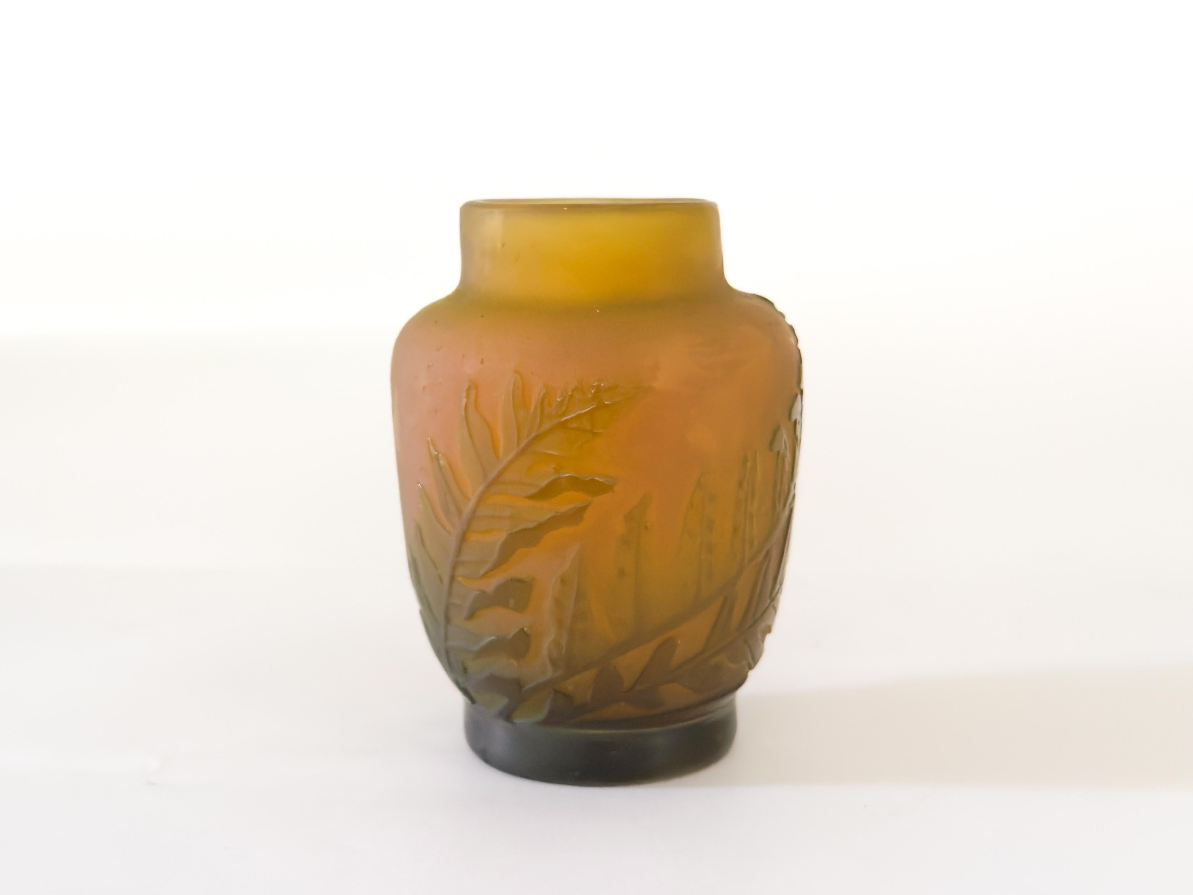 An acid etched vase decorated with green ferns against the opaque yellow
background.  
The cameo glass uses two colors layered, so that the color of the layer underneath becomes visible. 
‘Galle’ signed.