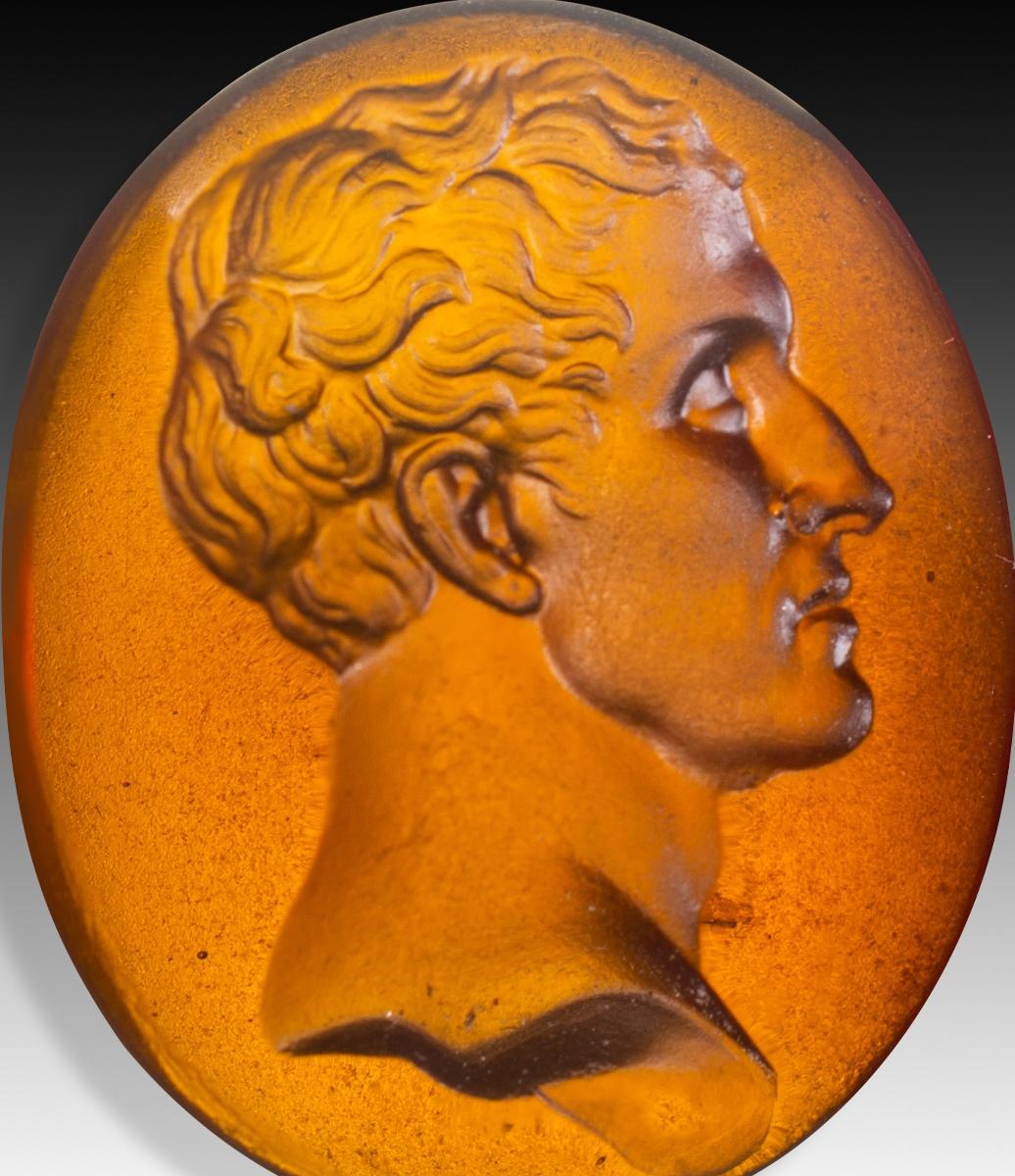 Cameo or intaglio, male portrait. Glass. Possibly Italy, 19th century. 
Male profile with short hair divided into wavy locks reminiscent, for example, of portraits of Julius Caesar and his dynasty. These types of pieces were created in a significant