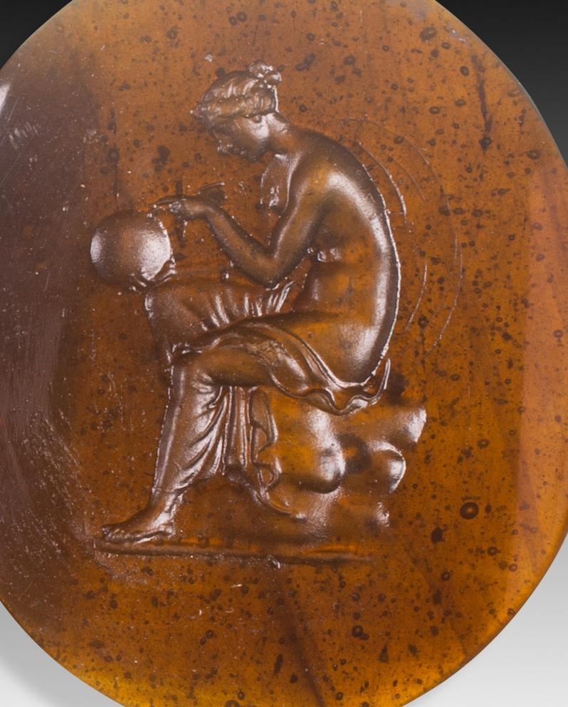  Camée ou intaille, Urania. Le verre. Peut-être Italie, 19e siècle. 
La figure féminine semi-nue qui apparaît assise et tient une sphère est souvent associée à la muse de l'astronomie et de l'astrologie, Urania. Comparez la pièce avec l'intaille de