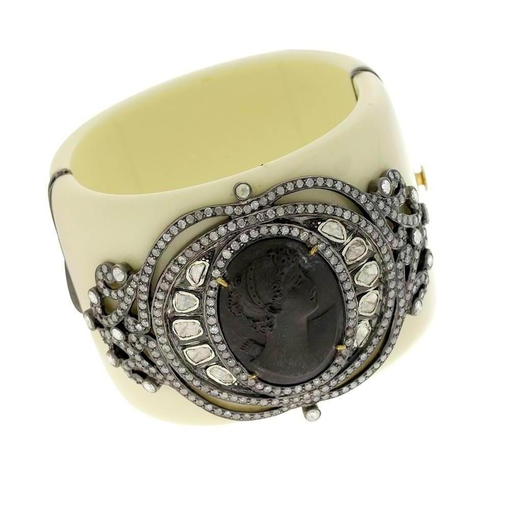 This gorgeous grey lava cameo with lady face is all designed with rosecut diamond motif around and put on a ivory color Bakelite cuff which opens from side and sits perfectly on the wrist. 

18Kt: 2.89gms
Diamond: 9.04Ct
Sl: 37.9gms
BAKELITE: