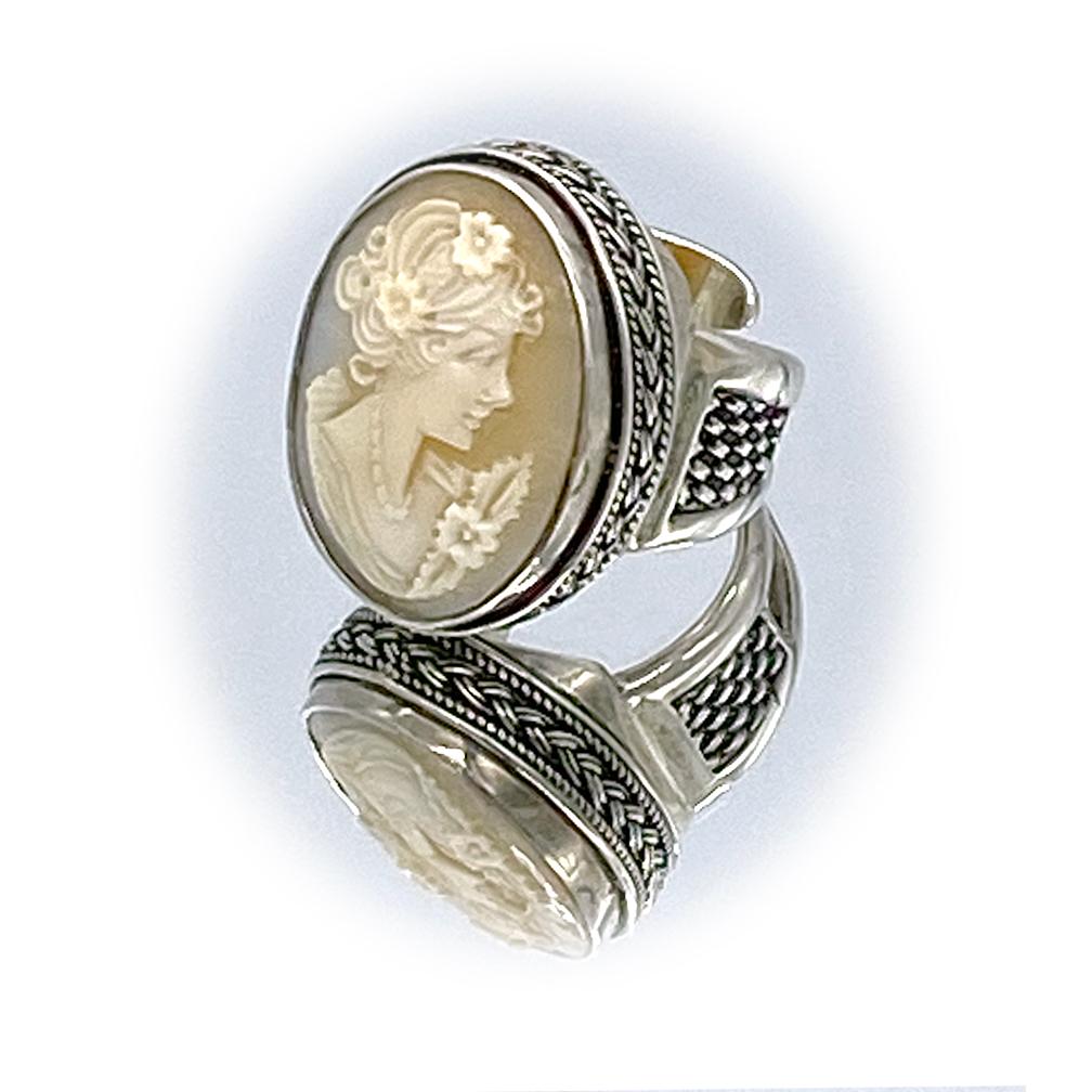This is a cameo sterling cocktail ring. A vintage 1 x .75 inch oval shape carved shall cameo is bezal set in a detailed ornate sterling silver adjustable ring. It's designed by an American designer, Alexander Kremer, and commissioned to a skillful